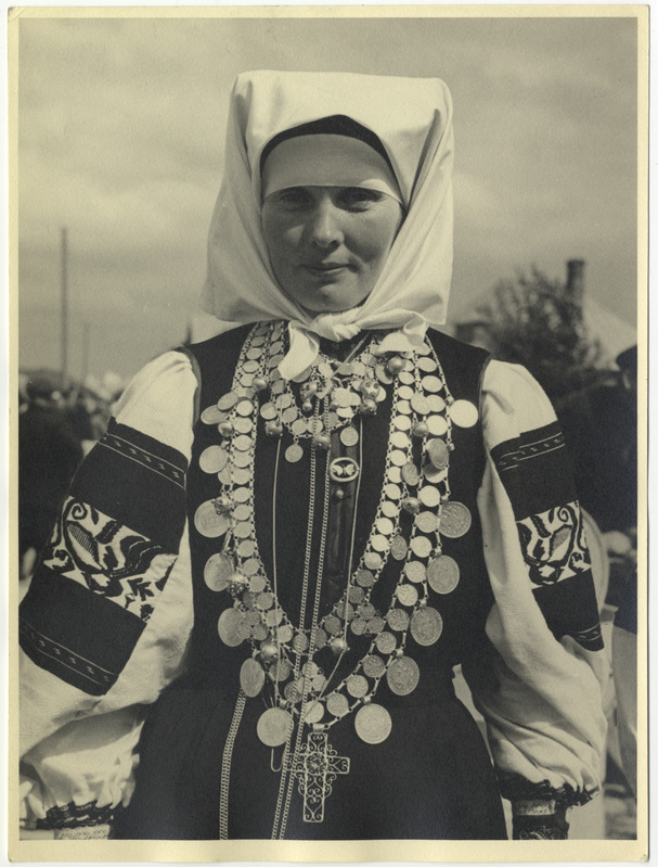 Rätikuga setu rahvariietes naine, hulga rahadega rist kaelas.
