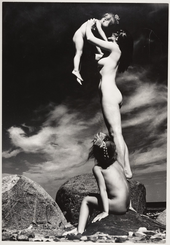 Rannas kivil seisev akt koos lastega.