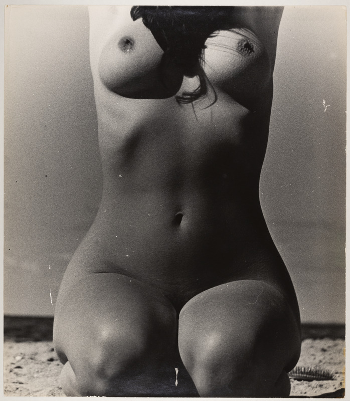 Põlvitav, ülestõstetud kätega akt rannas. Eestvaade.