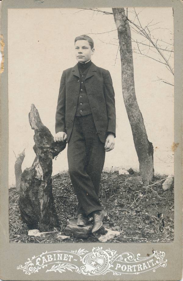 Ülikonnas noormees seismas puu kõrval 20 saj alguses.