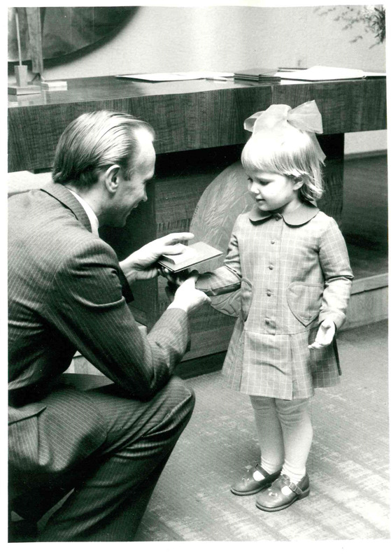Digitaalne kujutis. Tartu perekonnaseisuamet, Enn-Arno Sillari annab lapsele sünnimedali ja nimepäeva tunnistuse.  1985