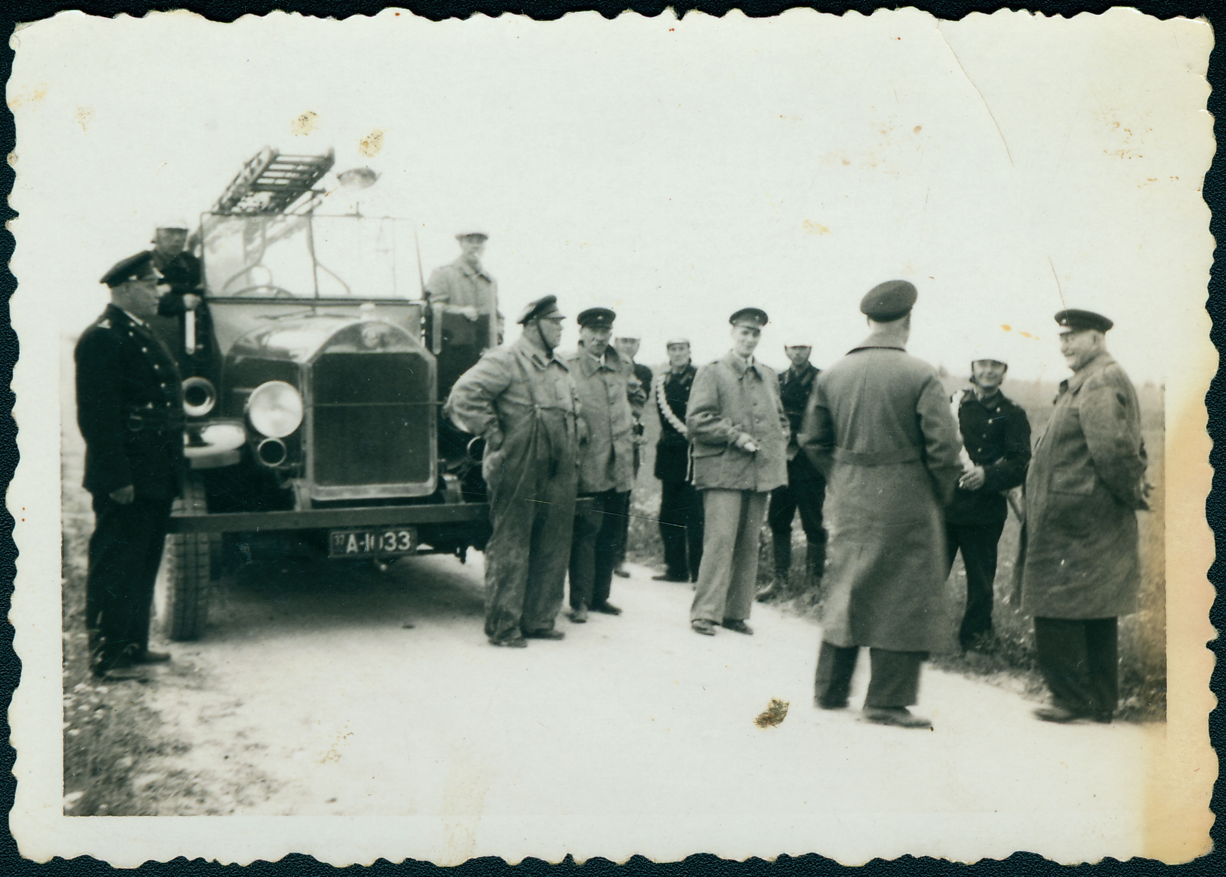 Grupp tuletõrjemundrites mehi tuletõrjeauto juures.