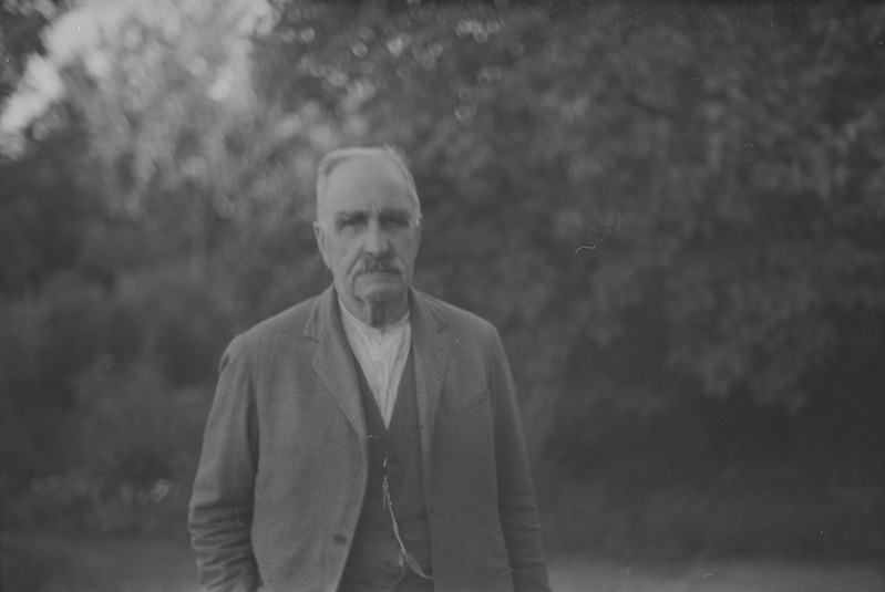 Vanem mees aias puude taustal