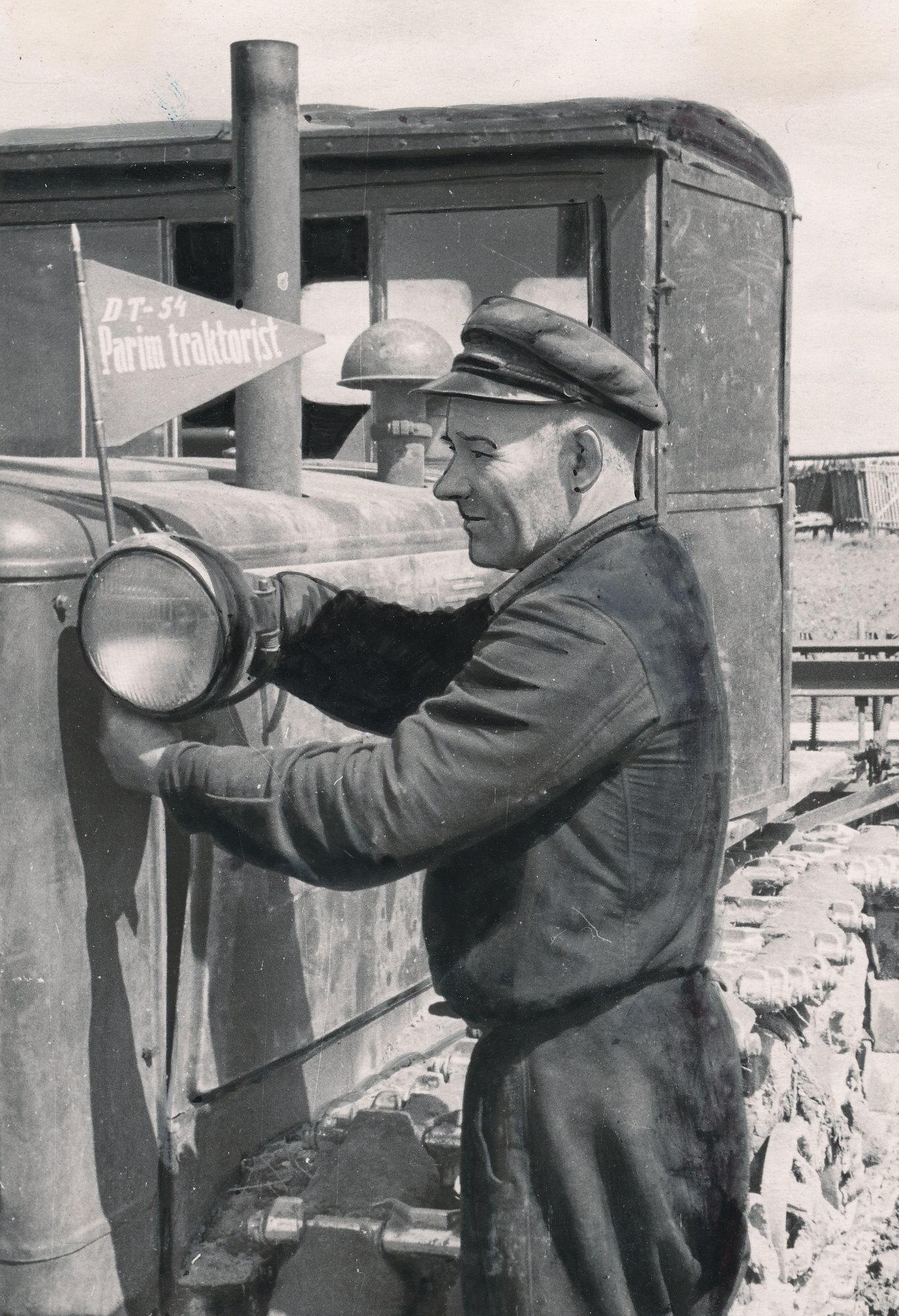 Foto. Kalinini nim. kolhoosi 2. brigaadi traktorist K. Ideon   traktorile rändvimplit kinnitamas juunis 1956.a.