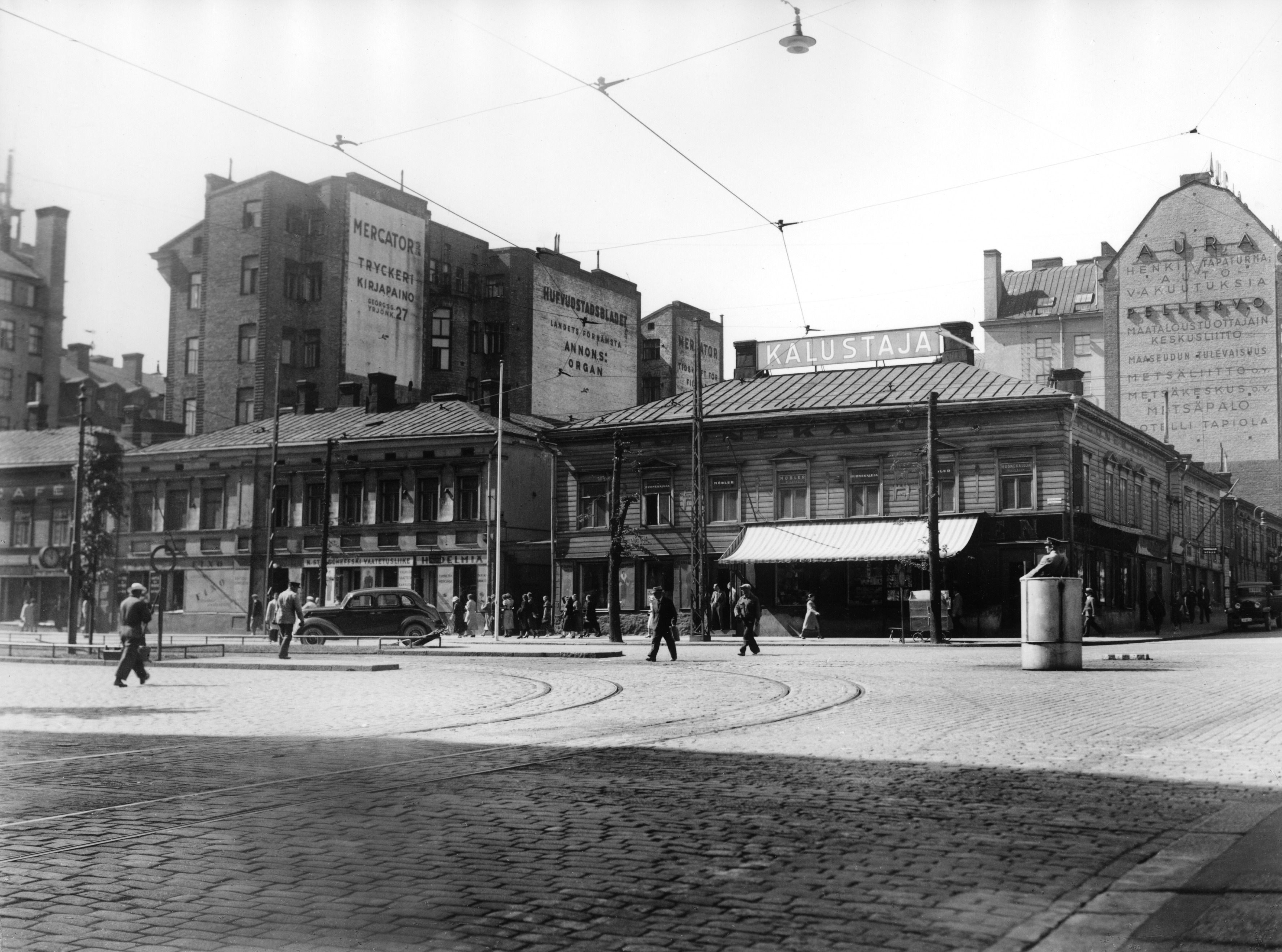 Heikinkatu 26, 24 (Mannerhiemintie 20) - Simonkatu 2, 4. Seinämainoksia: Mercator kirjapaino, Hufvudstadsbladet, Aura vakuutusyhtiö, Pellervo. Kalustaja-liikkeen nimikyltti.