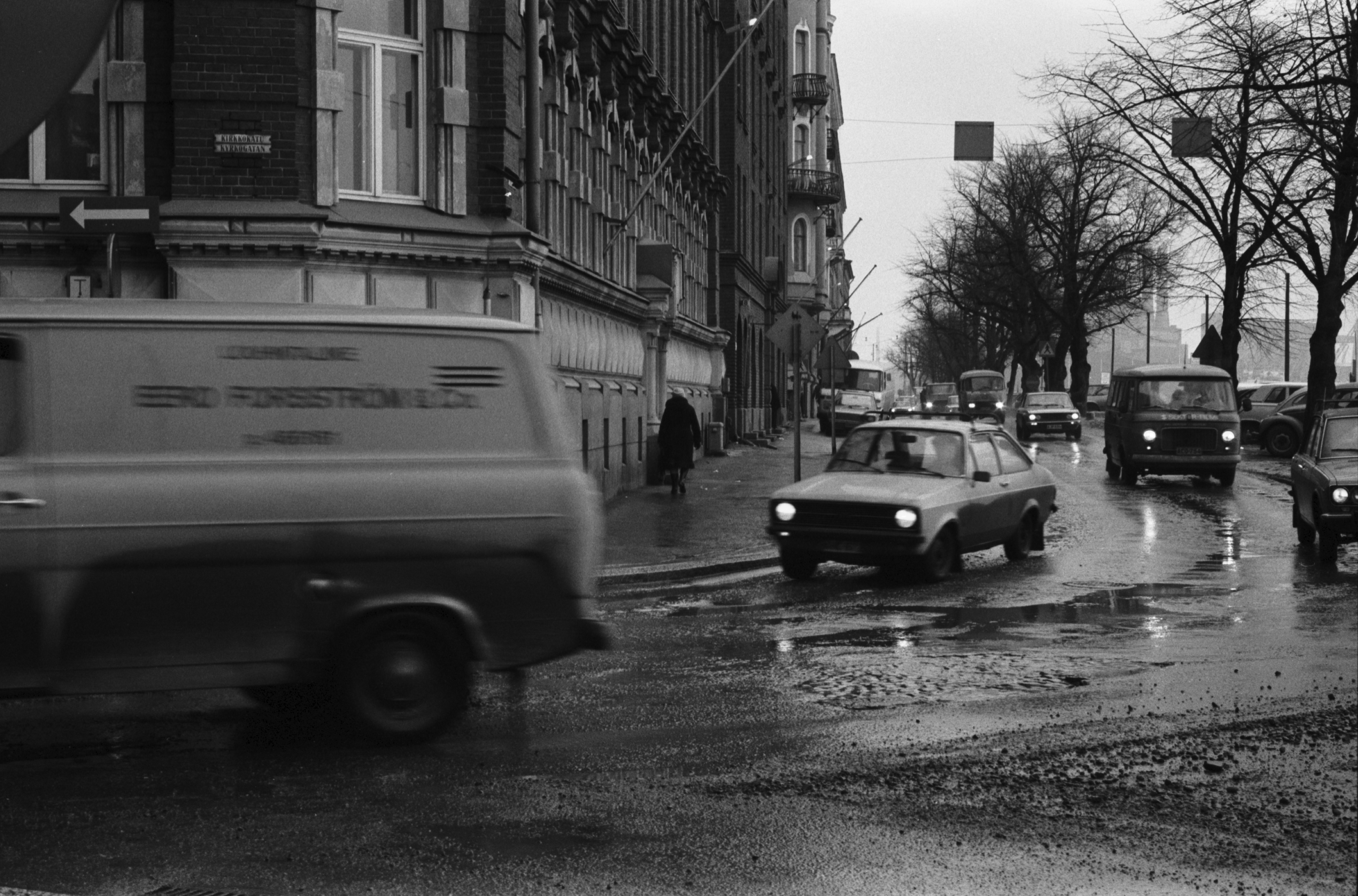 Pohjoisranta 6. Rapa roiskuu - liikennettä sadesäällä Pohjoisrannassa Kirkkokadun kulmassa. Näkymä Sörnäisten suuntaan.