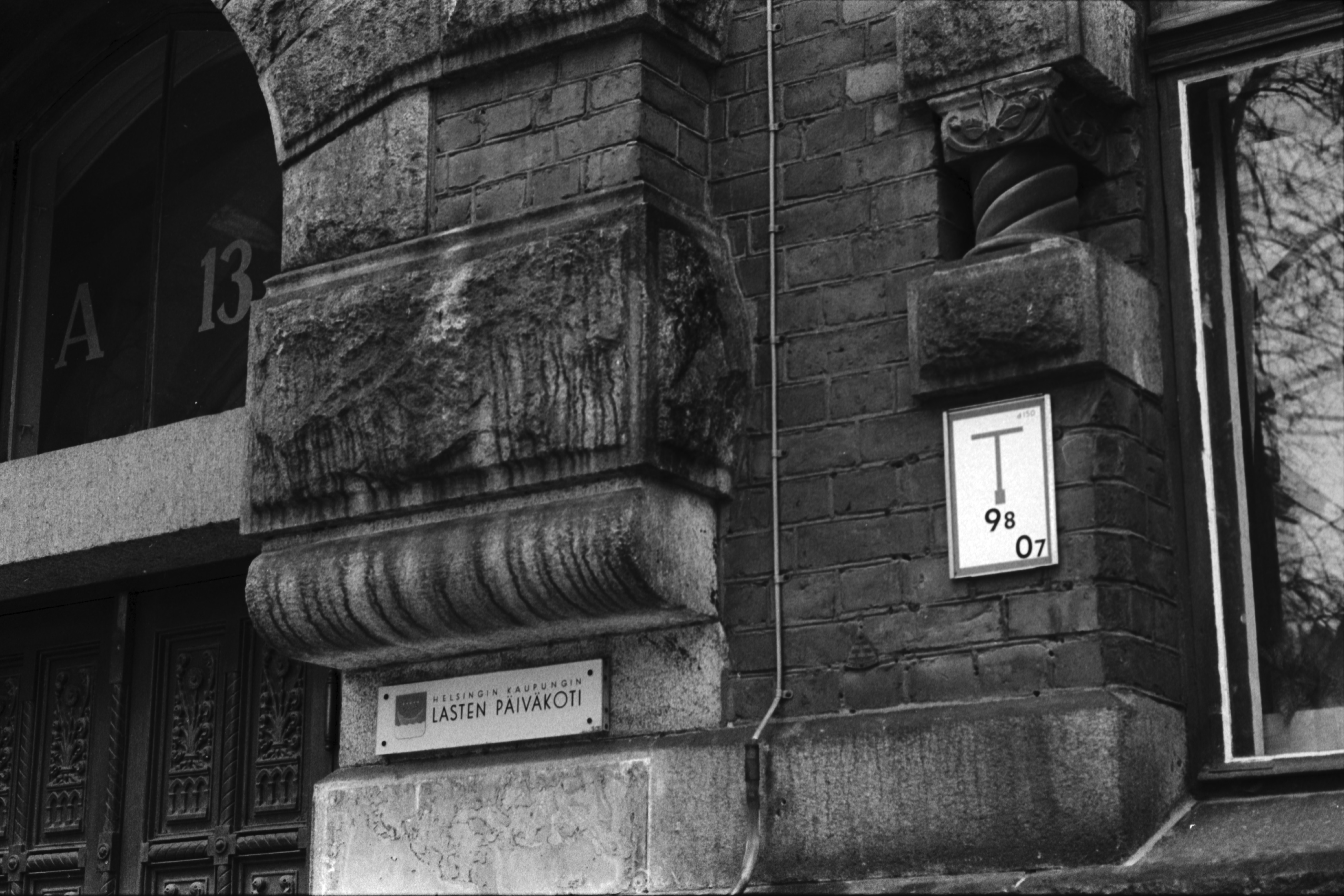 Rauhankatu 13. Yksityiskohtia Rauhankatu 13:n talon ulko-oven ja ikkunan pielessä. Seinässä teksti Helsingin kaupungin lastenpäiväkoti. Talon ensimmäisessä kerroksessa toimii Vironniemen päiväkoti.