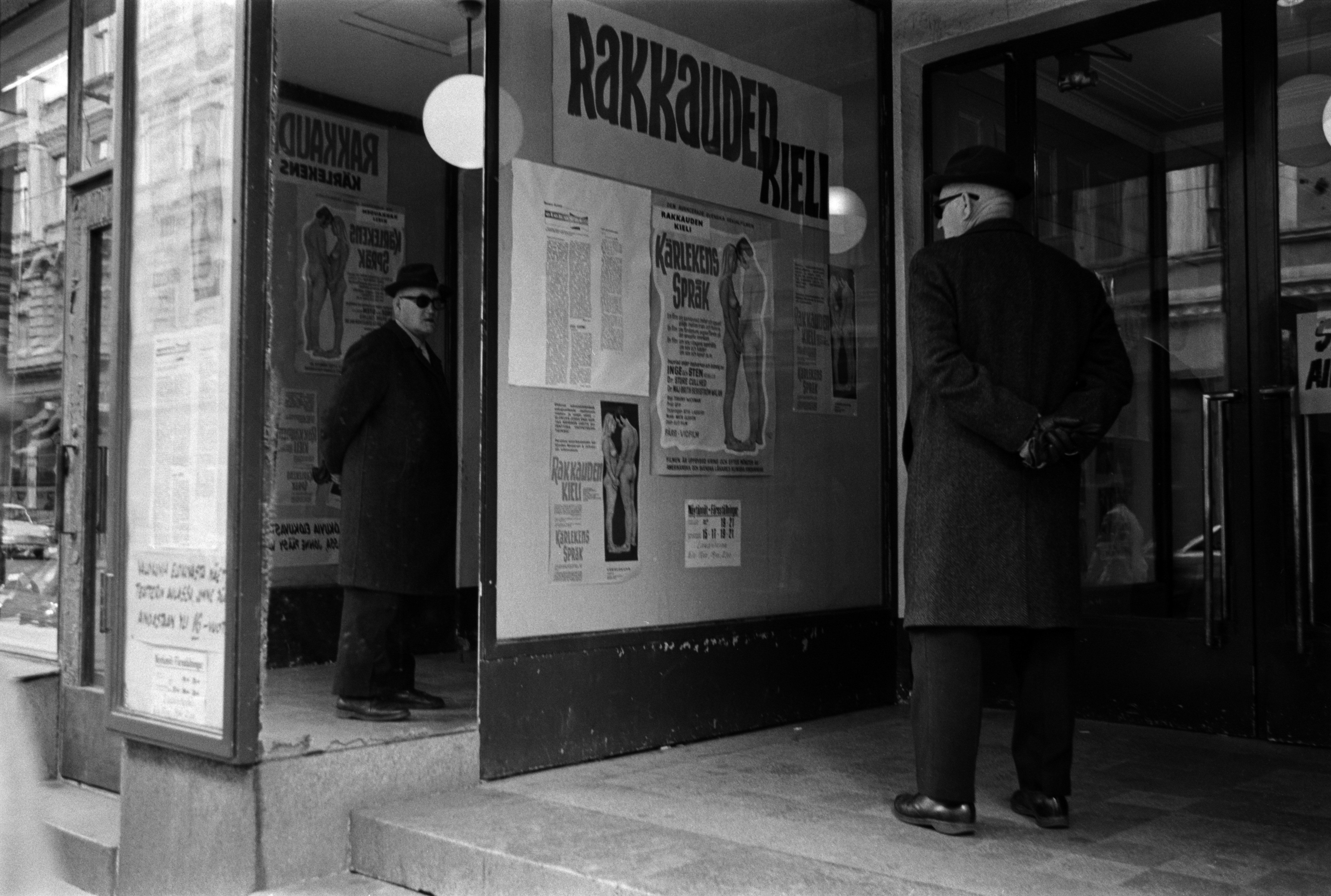 Iso Roobertinkatu 14. Mies katselemassa Rakkauden kieli -elokuvan mainoksia elokuvateatteri Astorin sisäänkäynnin edessä Iso Roobertinkadulla.