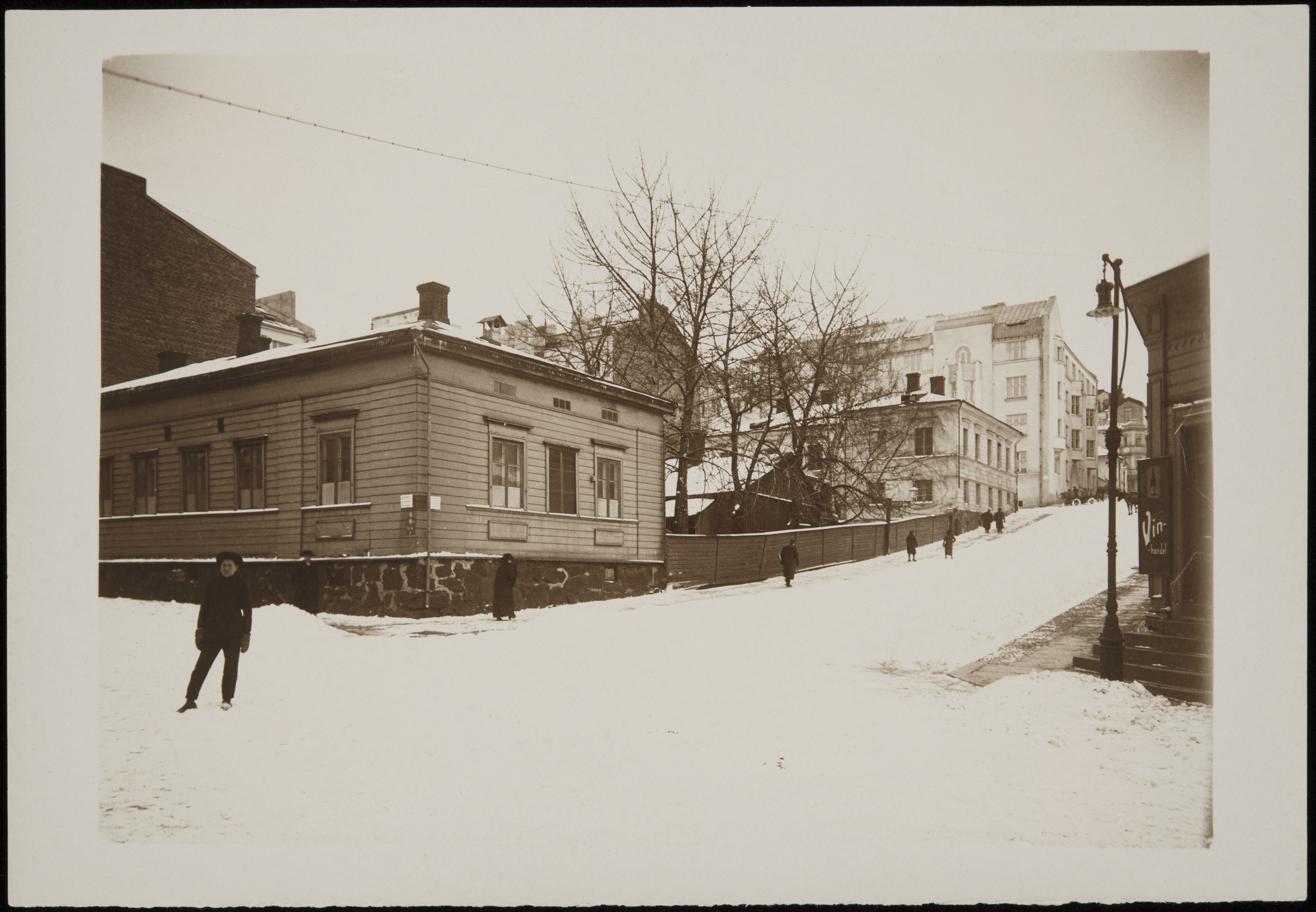 Talvinen näkymä Meritullinkadun ja Kirkkokadun risteyksestä luoteeseen. Vasemmalla Meritullinkatu 10a (Kirkkokatu 3), 10b (Rauhankatu 4) ja 12a (Rauhankatu 5), oikealla Meritullinkatu 5 (Kirkkokatu 1b), jonka kulmassa viinikauppa.