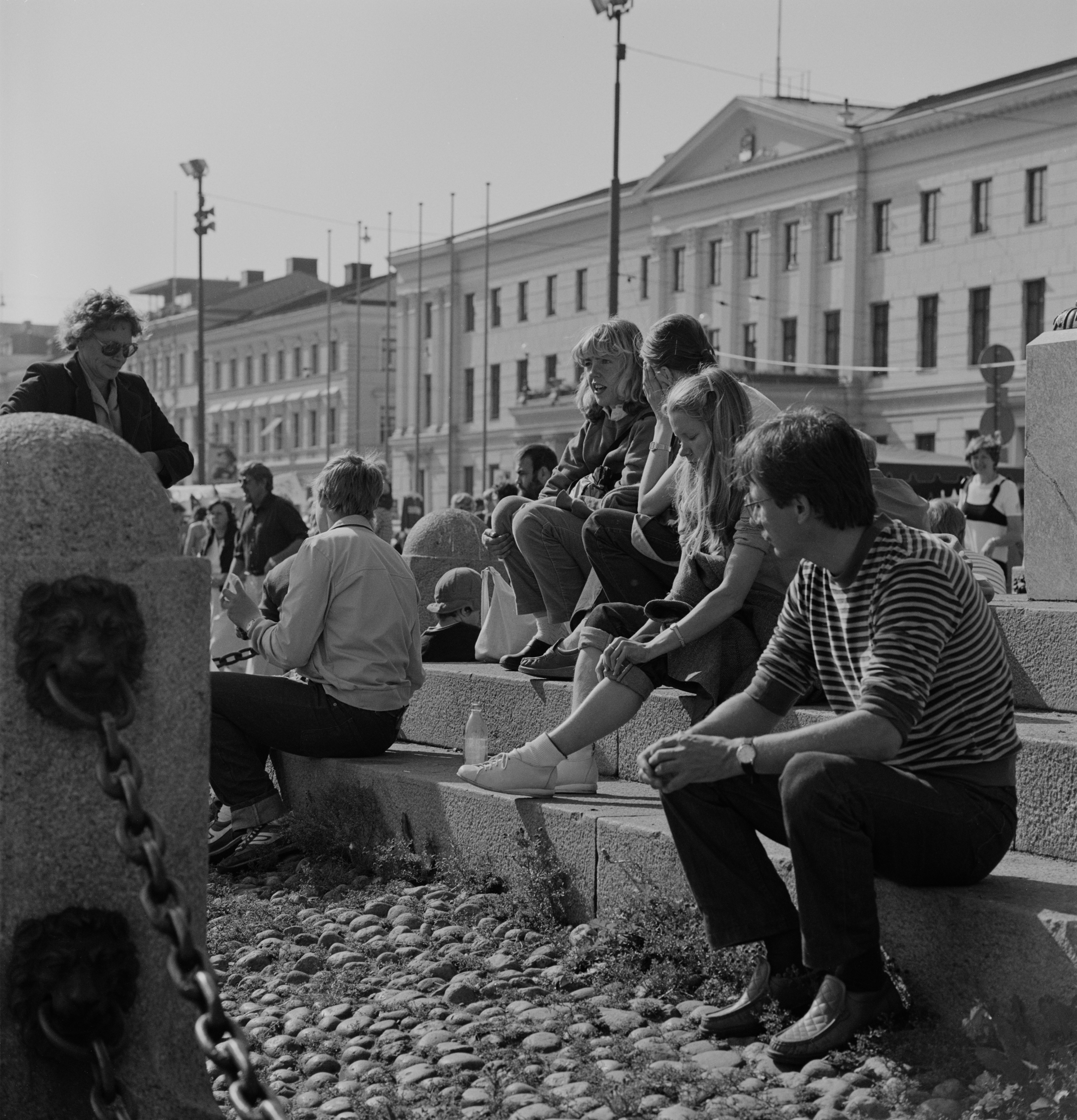 Kauppatori. Iltatori. Ihmisiä istumassa Keisarinnan kiven jalustalla.