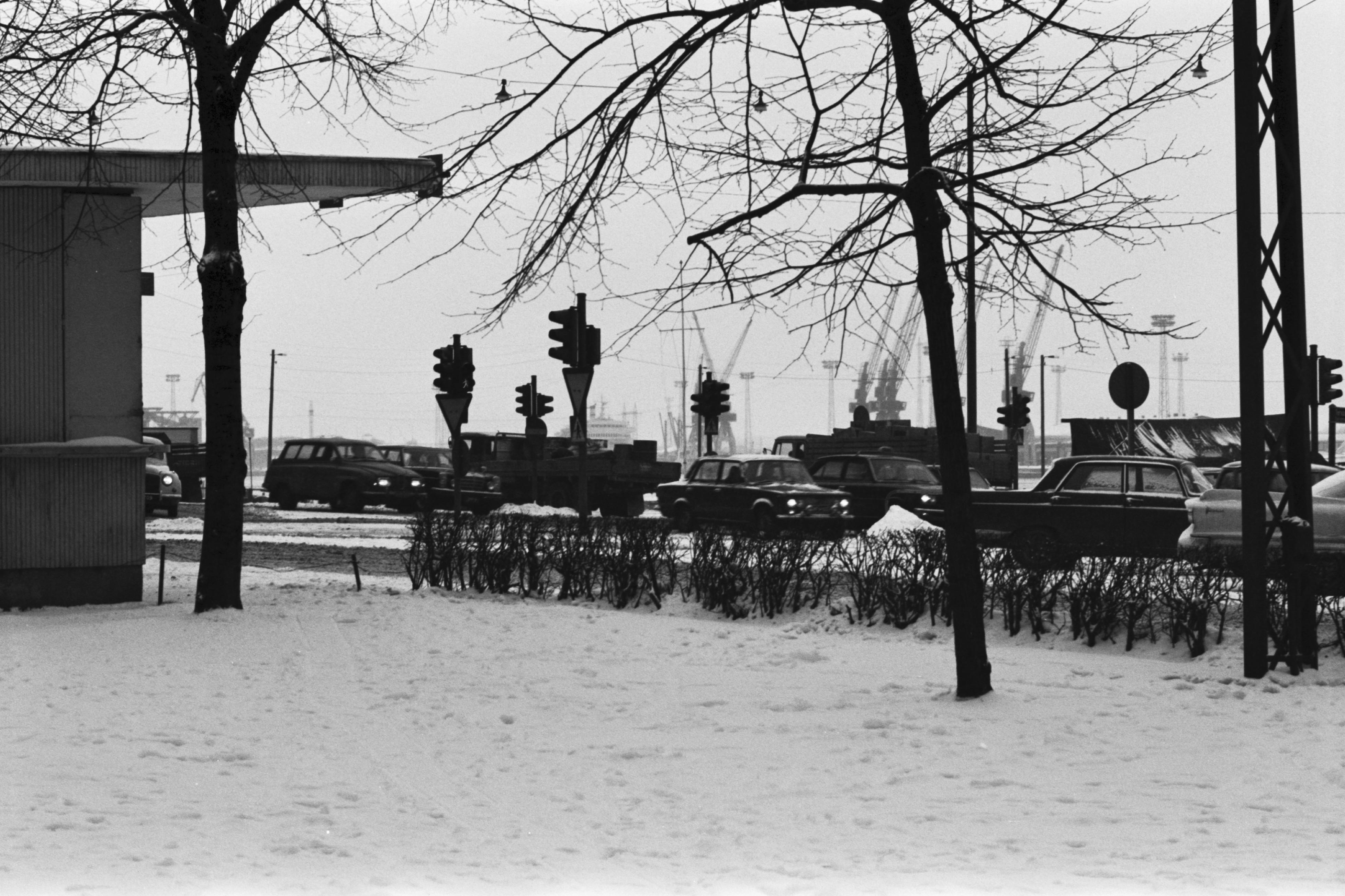 Kruununhaka, Pohjoisranta. Näkymä lumisesta Liisanpuistikosta koilliseen, Pohjoisrannan suuntaan. Vasemmalla lippakioskin kulma. Kadulla autoja ja liikennevalotolppia. Taustalla Sompasaaren nostokurkia.