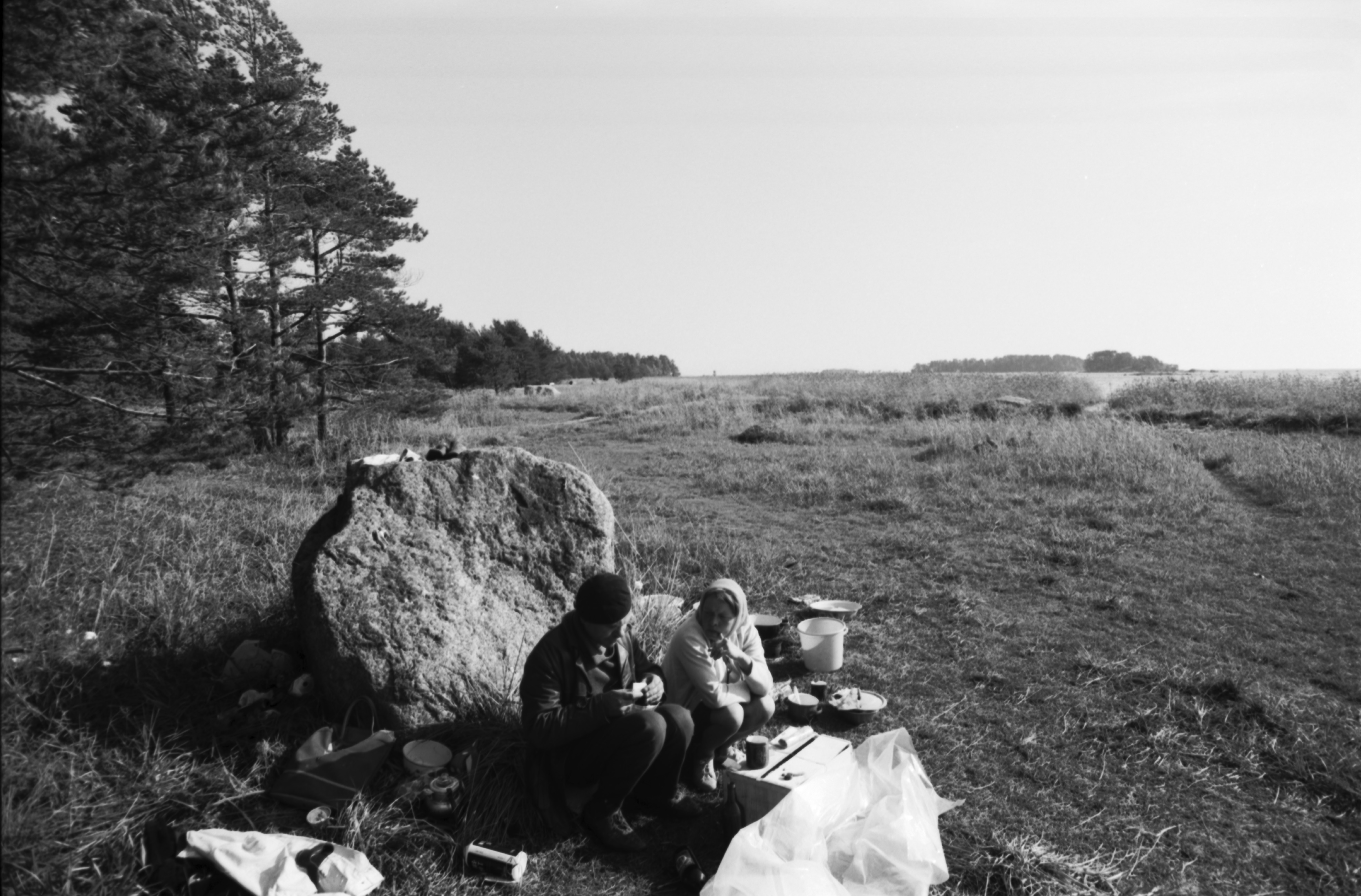 Kallahdenniemi. Mies ja nainen ruokailemassa kiven kupeessa Kallahdenniemen rannassa lähellä telttaa, jossa vielä syksyllä asustavat.