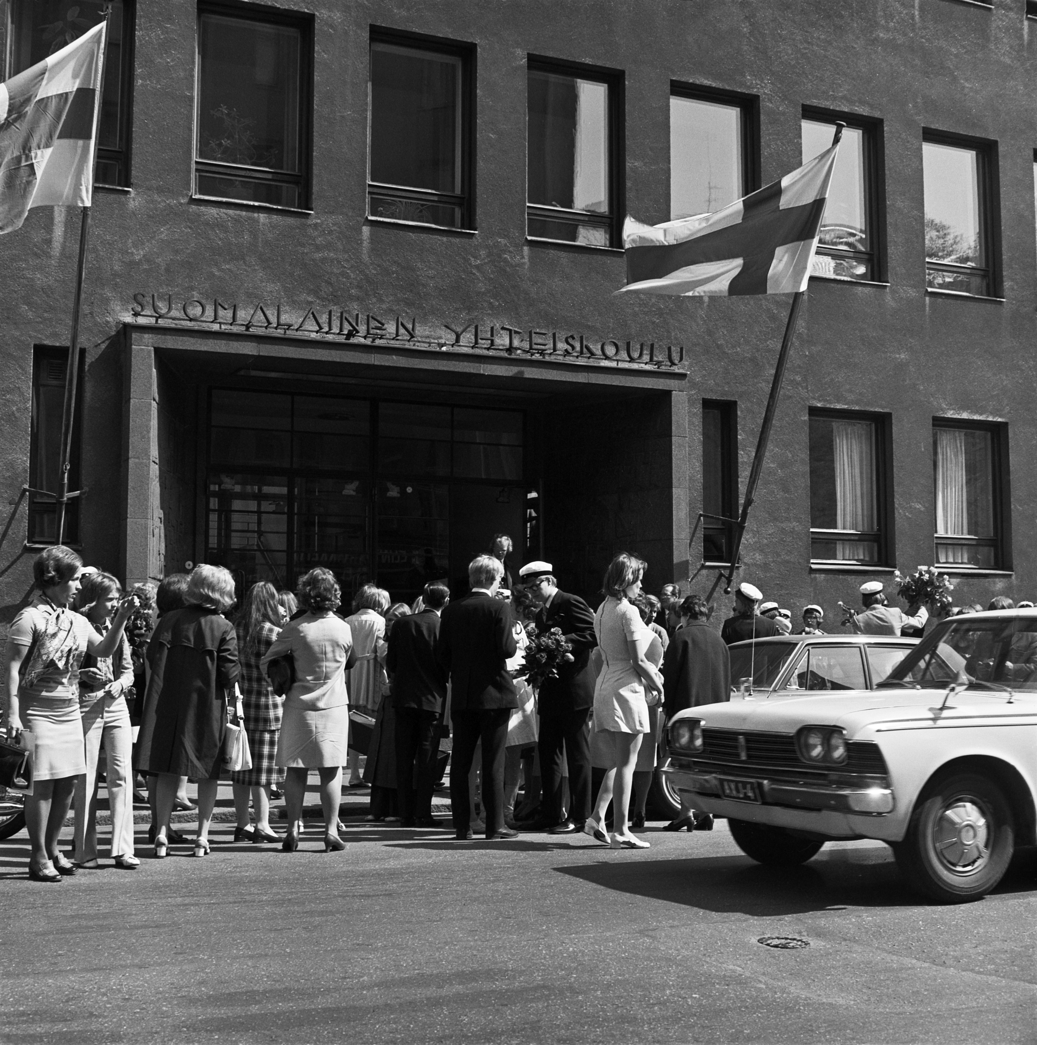 Suomalaisen yhteiskoulun uusia ylioppilaita koulunsa edustalla.