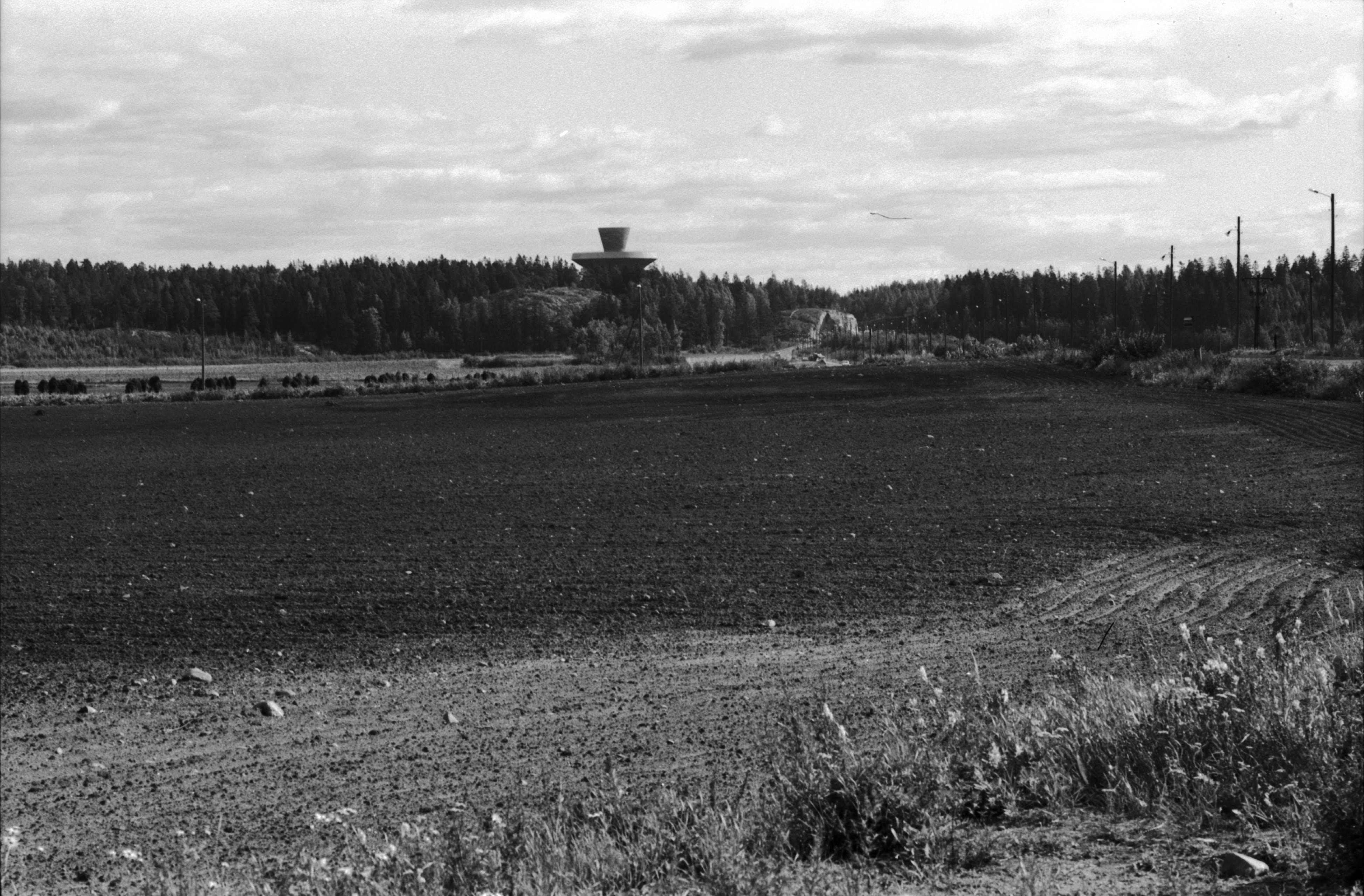 Näkymä Viikin Latokartanon pellolta kaakkoon. Oikealla Viikintie ja Herttonemen satamarata. Taustalla Myllypuron vesitorni.