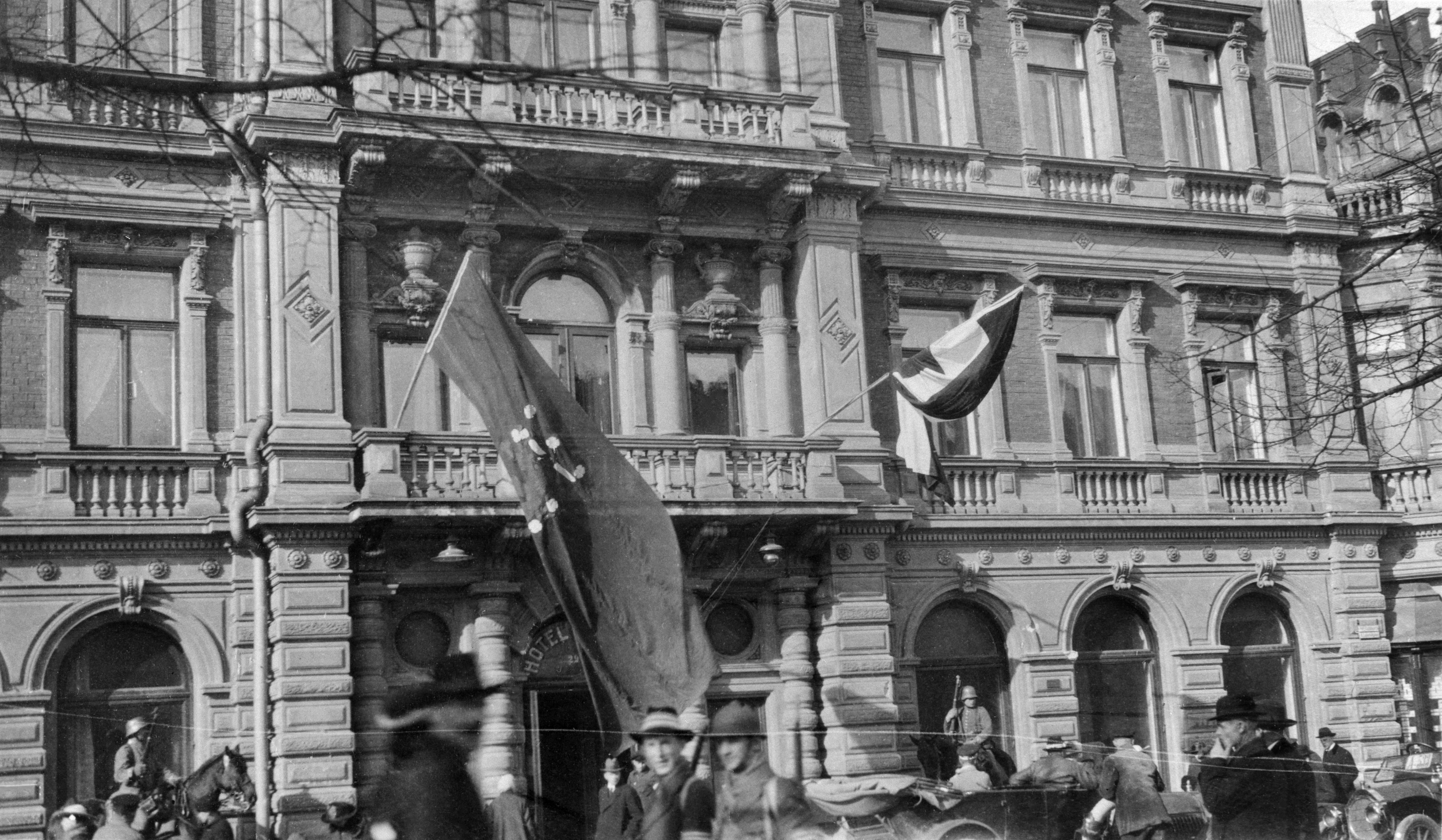 Helsingin valtaus 1918, saksalaisten esikunta hotelli Kämpissä, Pohjoisesplanadi 29. Vasemmalla punapohjainen Suomen lippu, oikealla vihreä-valko-musta Saksan valtakunnanlippu.