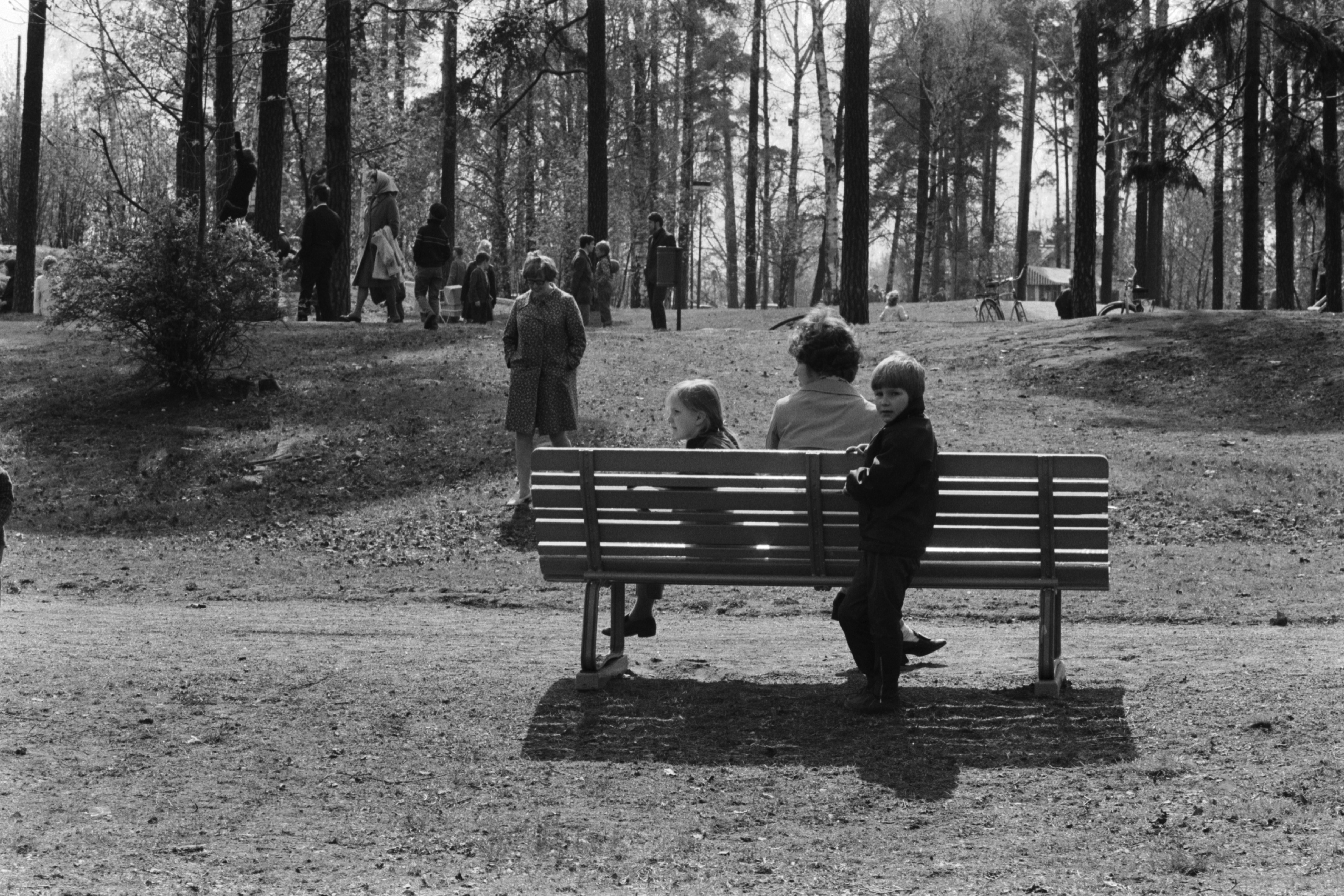 Sibeliuksen puisto. Helsingin juhlaviikot. Nainen ja kaksi lasta penkillä puistotapahtuman aikaan aurinkoisessa Sibeliuksen puistossa.