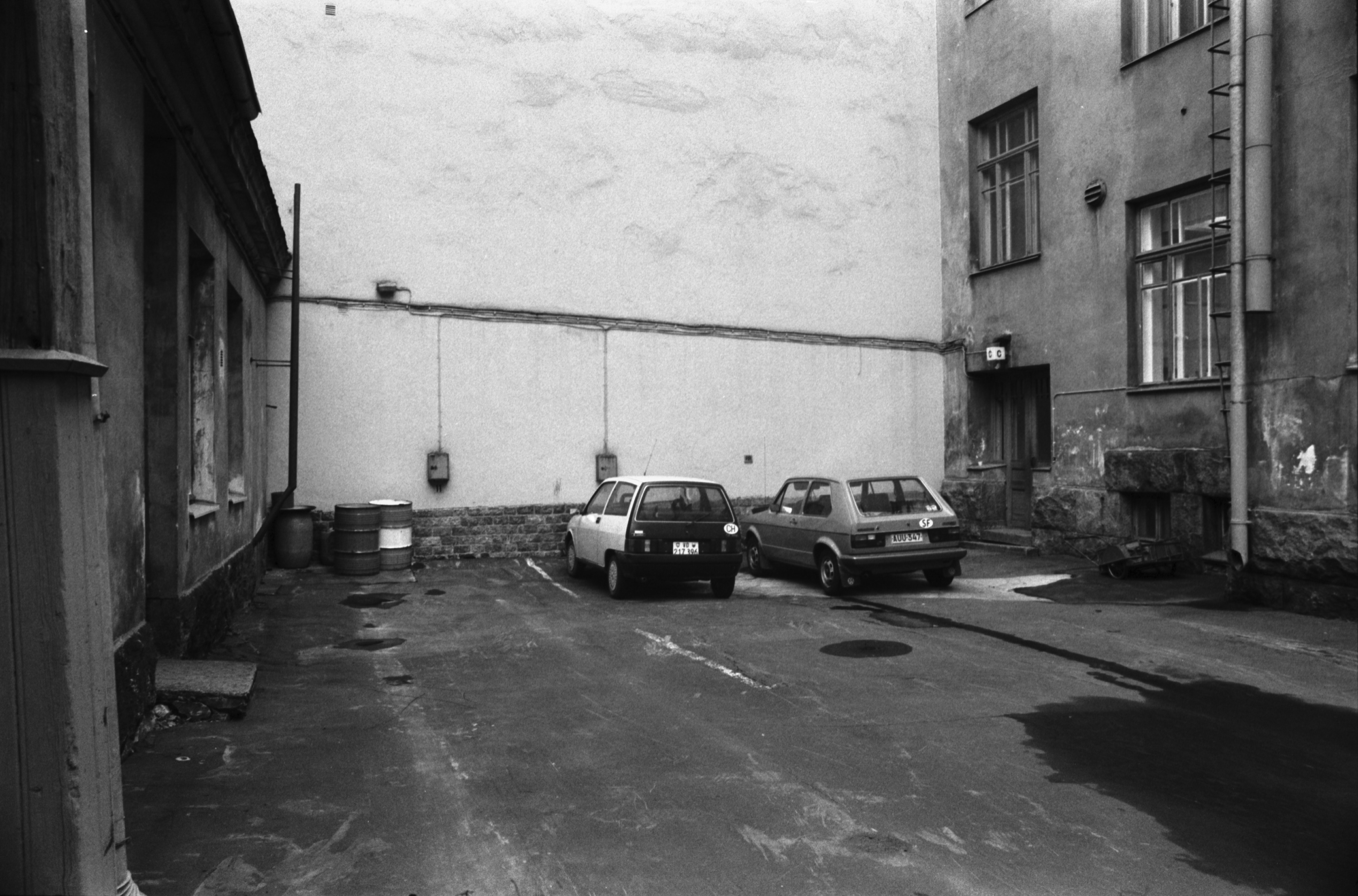 Rauhankatu 13. Rauhankatu 13:n pihan itäinen pää. Vasemmalla piharakennus, keskellä pari autoa, oikealla C-portaan sisäänkäynti.