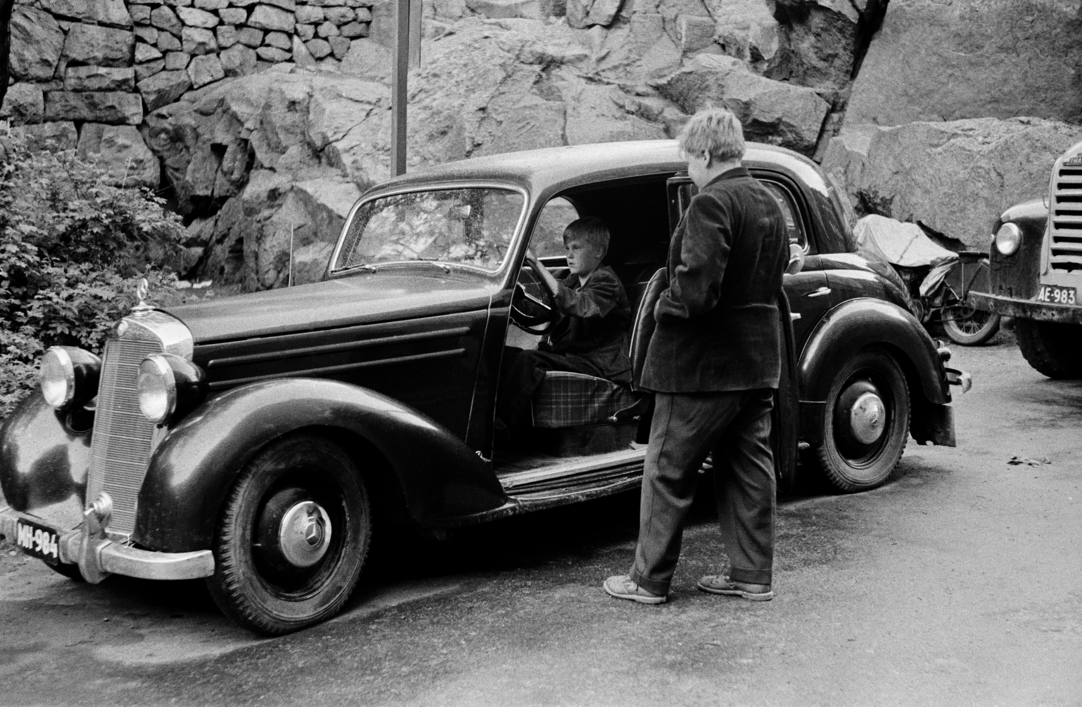 Kaksi poikaa henkilöauton (merkki Mercedes-Benz) luona Agricolankuja 2:n edessä, nykyisen Agricolanpuistikon kohdalla.
