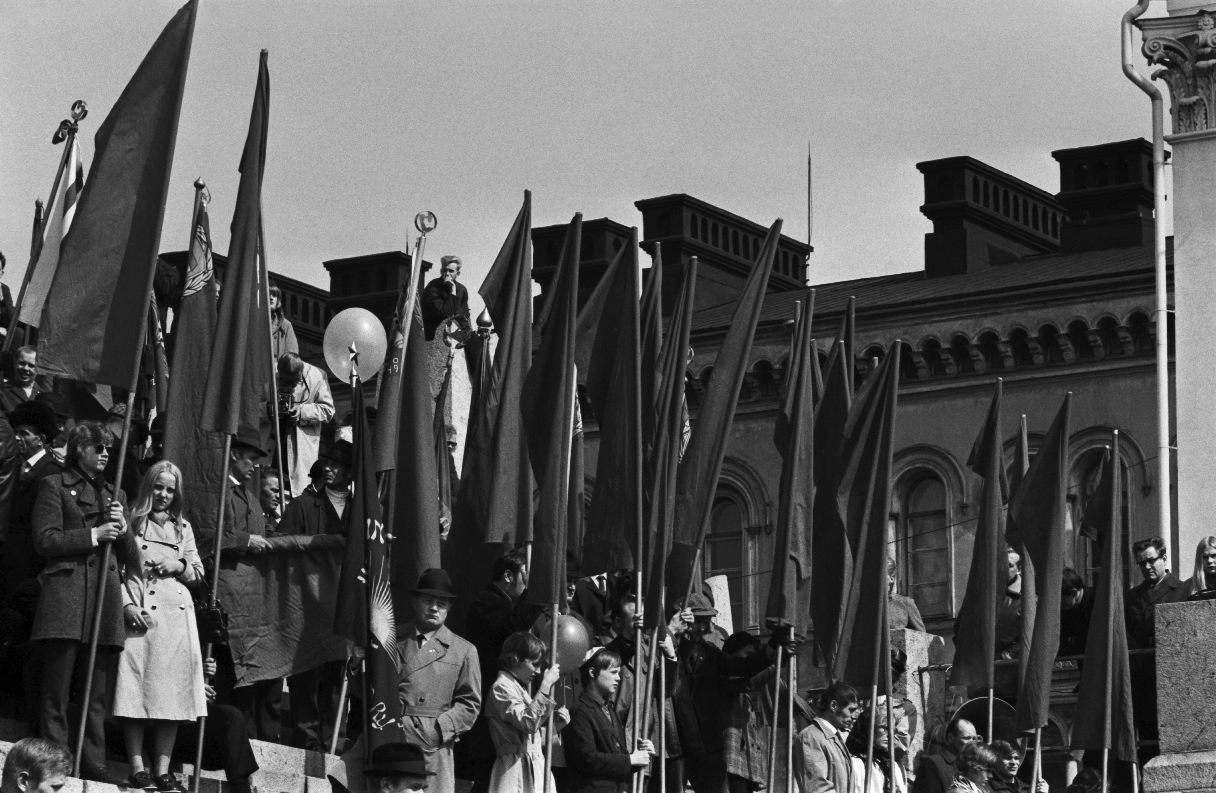 Hallituskatu 7. Ihmisiä punalippujen kanssa seisomassa Tuomiokirkon portailla työväen vappujuhlassa 1.5.1970.