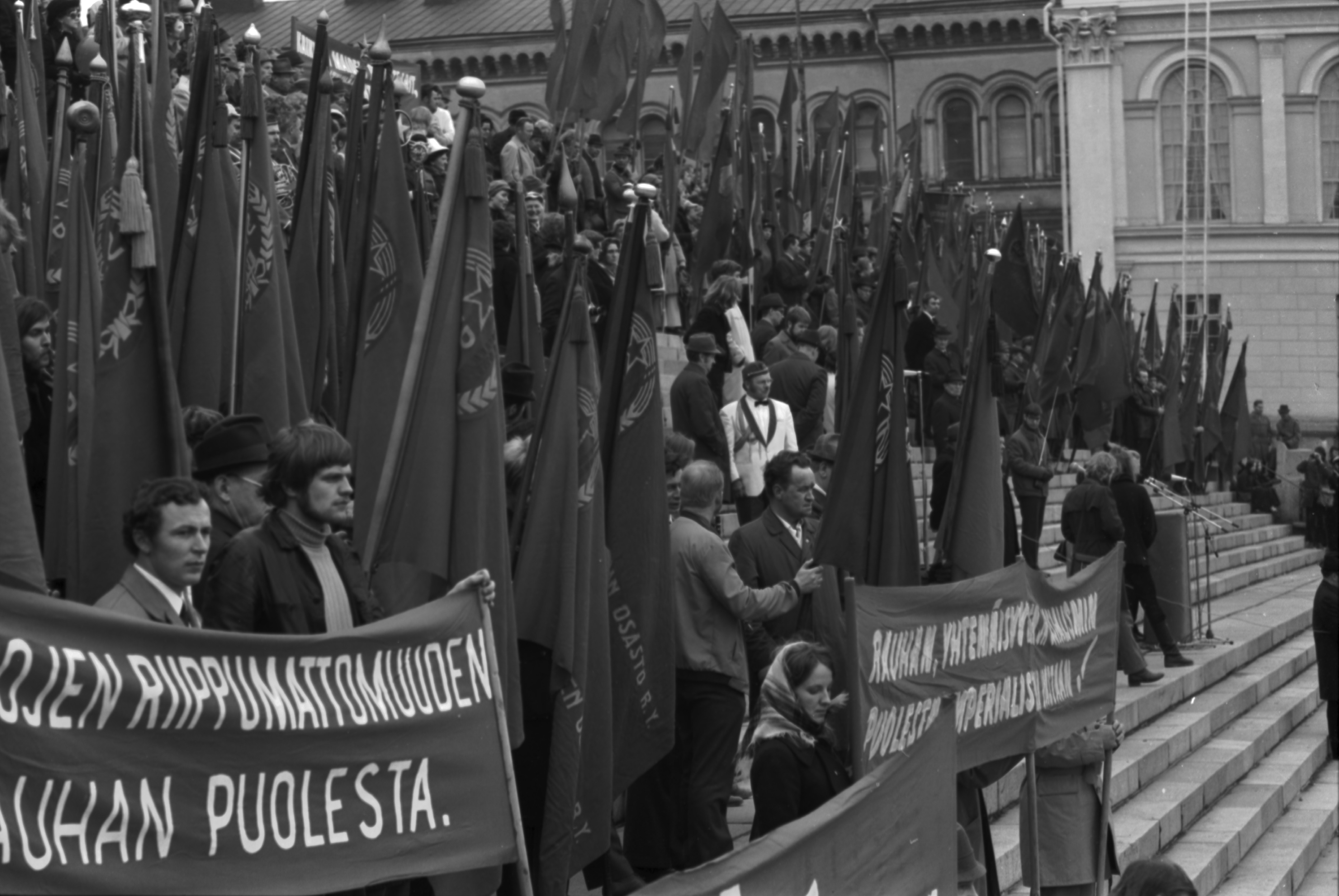 Hallituskatu 7. Työväen vappujuhlaan osallistuvia ihmisiä banderolleineen ja lippuineen Tuomiokirkon portailla 1.5.1972.