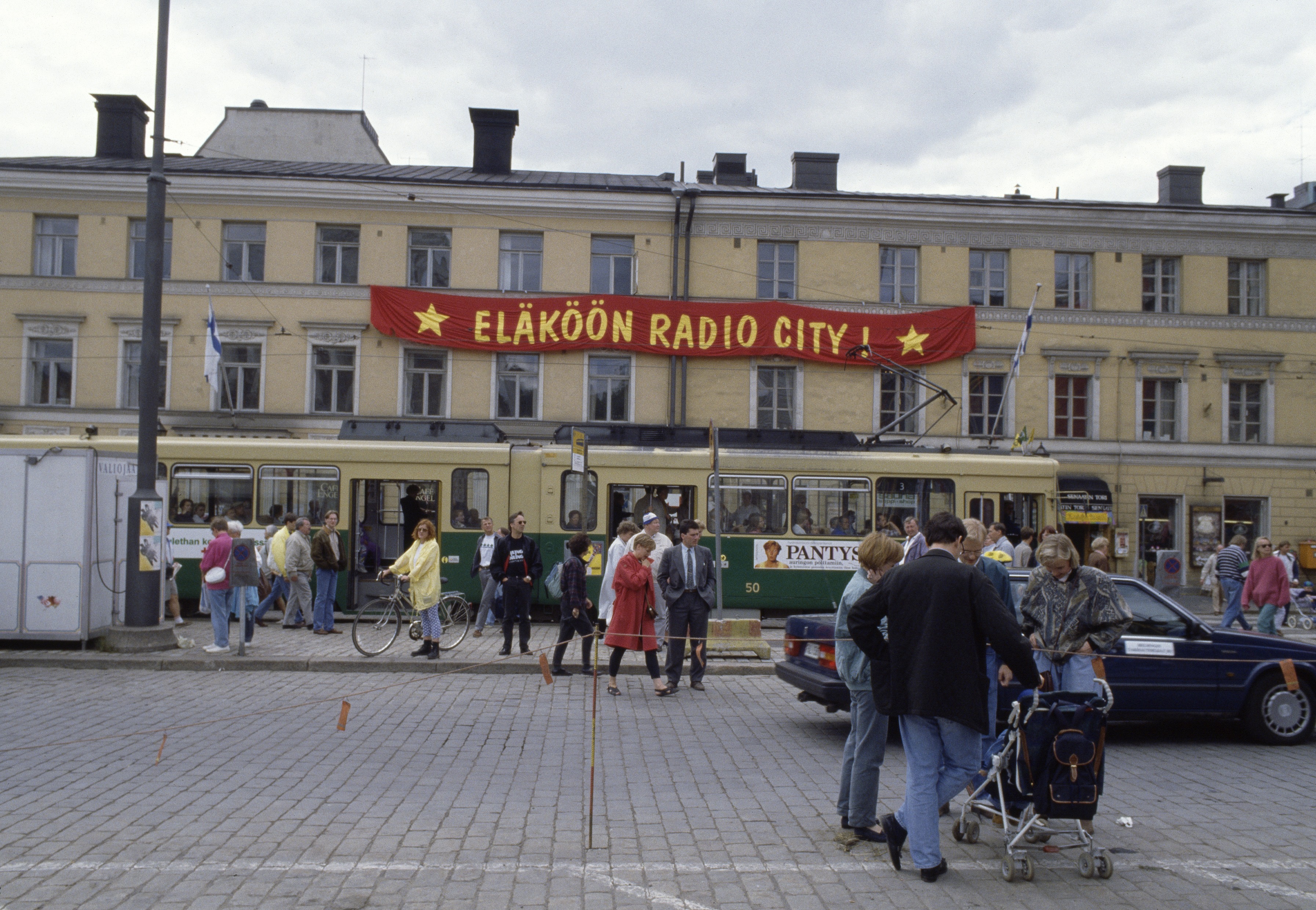 Leningrad Cowboys -yhtyeen ja Puna-armeijan kuoron Total Balalaika Show -konserttia valmistellaan Senaatintorilla Helsinki-päivänä 1993. Taustalla Aleksanterinkatu 22, 24. Radio Cityn banderolli.