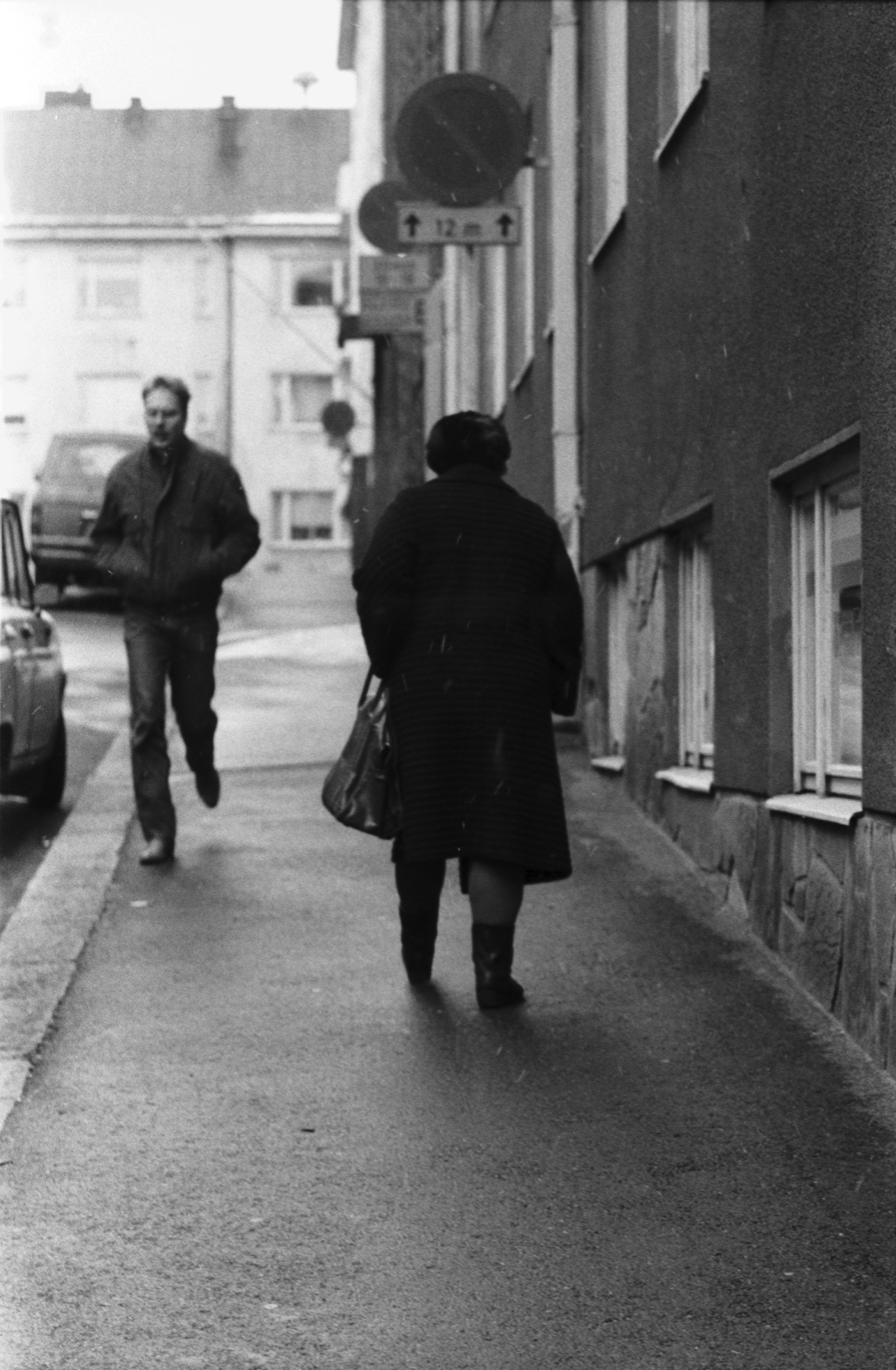Kulmakatu 3b. Mies ja nainen kävelemässä Kulmakatu 3b:n edessä alkutalven kevyessä räntäsateessa. Näkymä Kristianinkadun suuntaan.