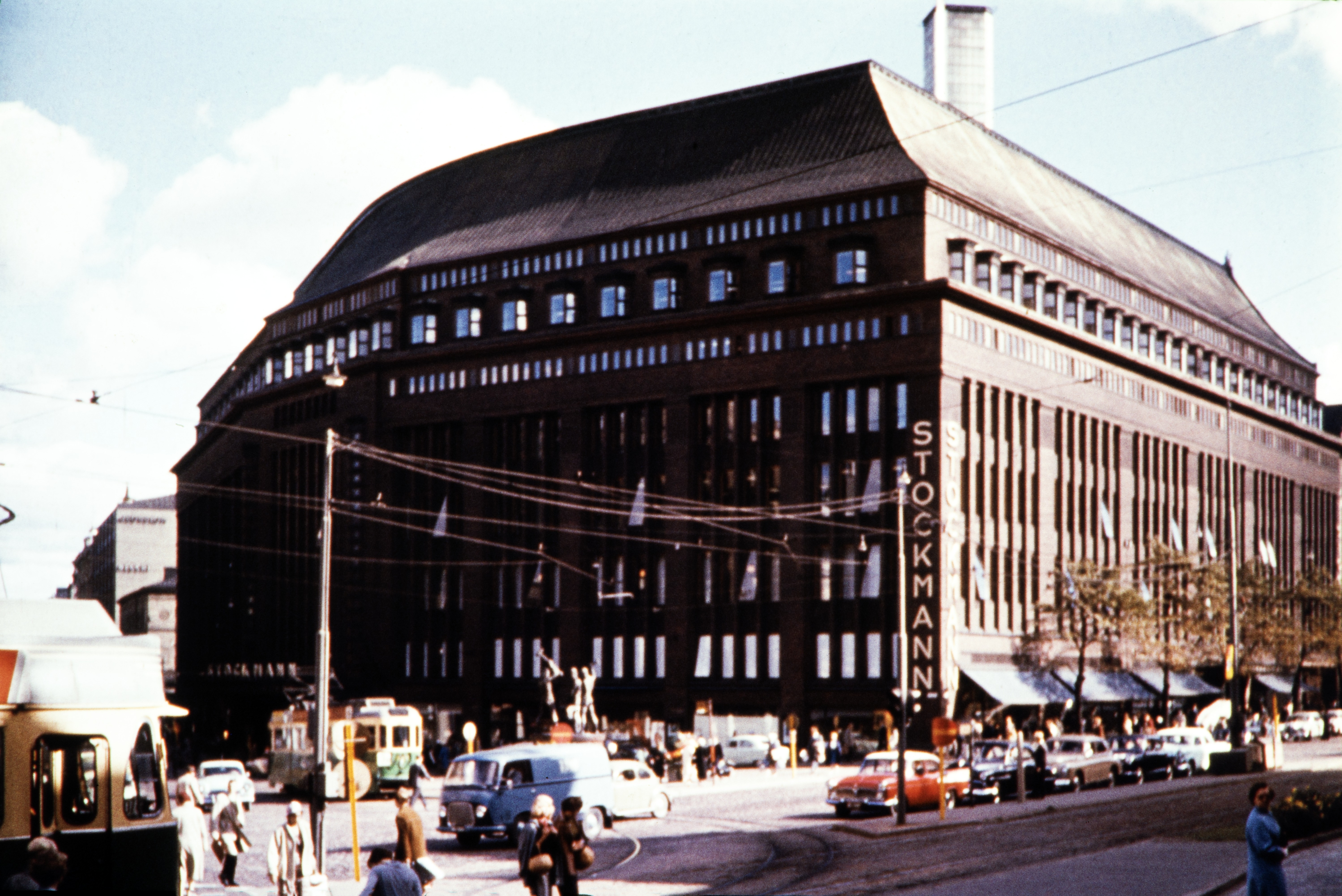 Stockmannin tavaratalo, Aleksanterinkatu 52. Näkymä Mannerheimintie 16:n kohdalta. Rakennus on toteutettu yleisessä suunnittelukilpailussa toisen palkinnon saaneen Sigurd Frosterusin ehdotuksen pohjalta. Rakentaminen aloitettiin basaarirakennuksella, ja varsinainen tavaratalo valmistui ensin 1920-luvun puolivälissä nelikerroksena. Lopulliseen kahdeksan maanpäällistä kerrosta käsittävään korkeuteen se valmistui 1930.