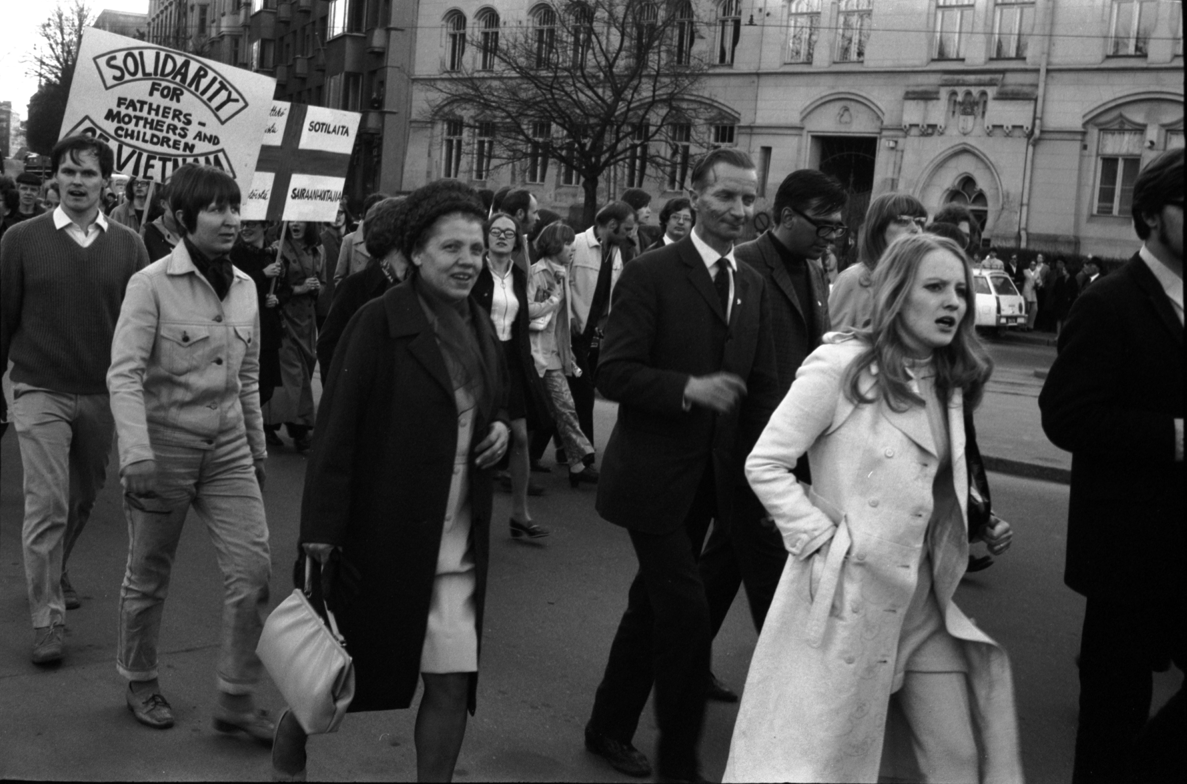 Vuorimiehenkatu 1. Eri ikäisiä ihmisiä Vietnamin sodan vastaisessa mielenosoituskulkueessa Laivasillankadulla Vuorimiehenkadun kulmassa. Taustalla Vuorimiehenkatu 1.