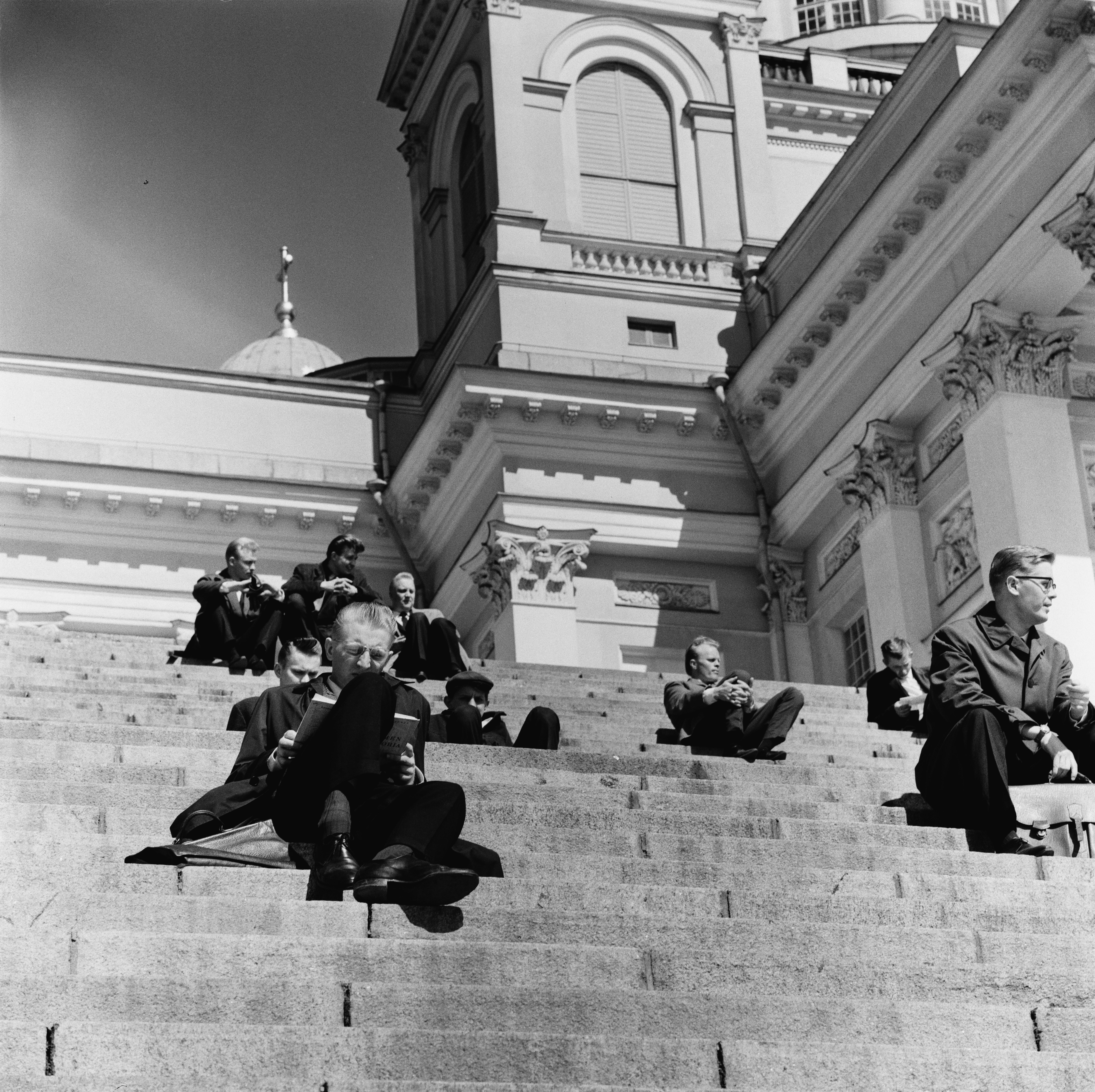 Ihmisiä istumassa Tuomiokirkon portailla.
