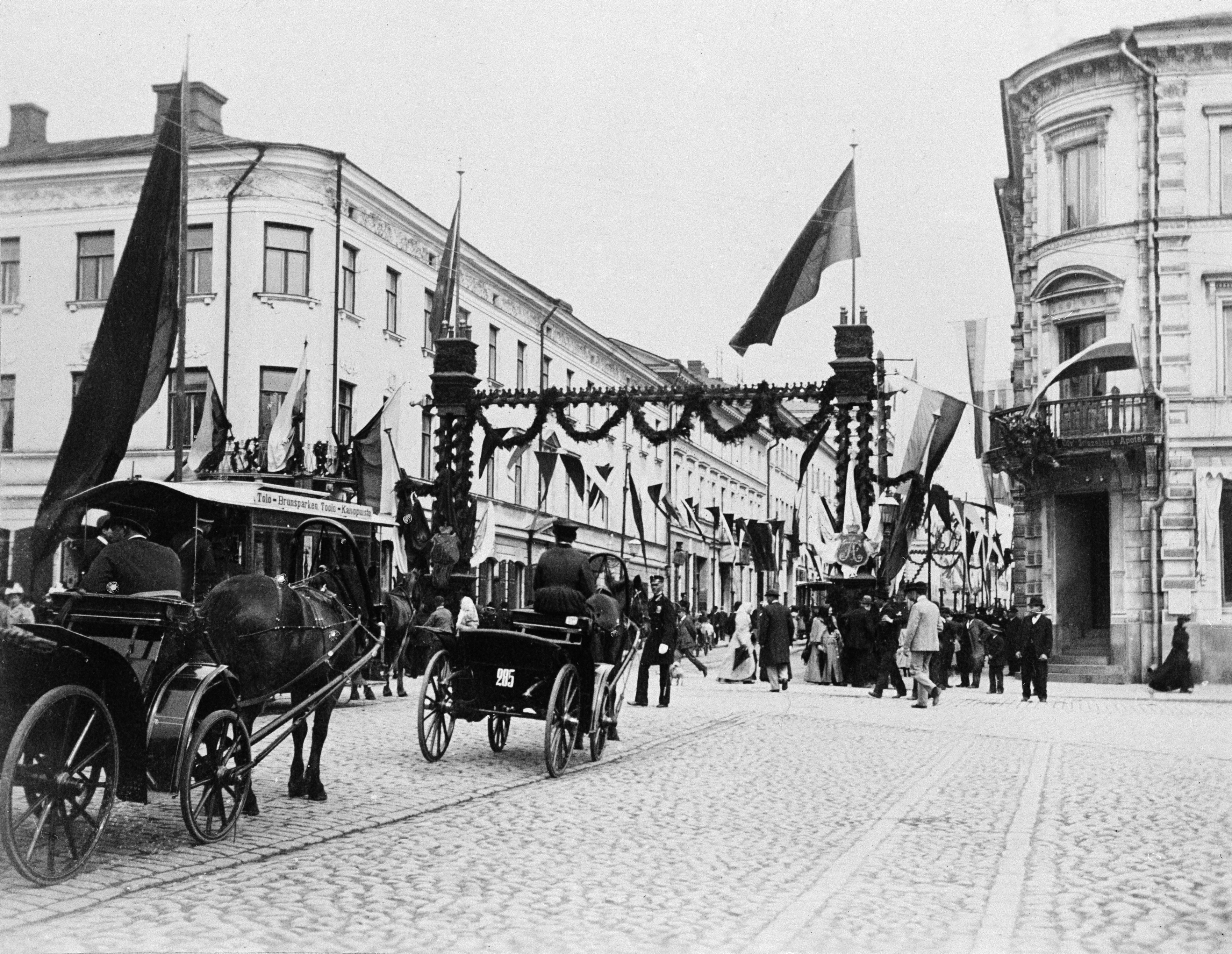 Juhlakoristelua Unioninkadulla keisari Nikolai II:n kruunajaisten kunniaksi. Vasemmalla Unioninkatu 28 - Pohjois-Esplanaadikatu (= Pohjoiseplanadi) 19, oikealla Unioninkatu 23 - Pohjois-Esplanaadikatu (= Pohjoisesplanadi) 17.