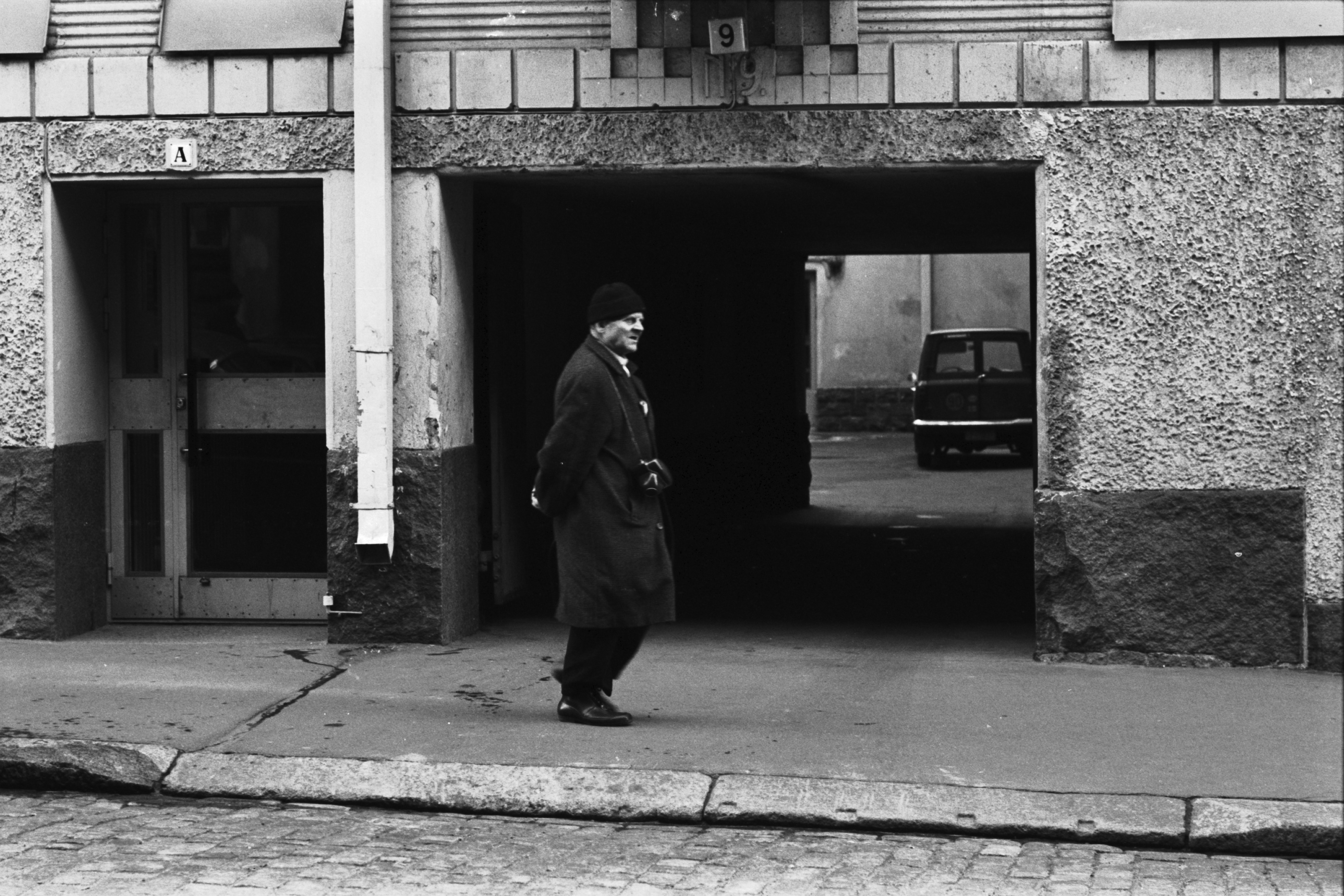 Kruununhaka, Liisankatu 9. Mies kulkemassa kamera kaulassa Liisankatu 9:n porttikäytävän kohdalla.