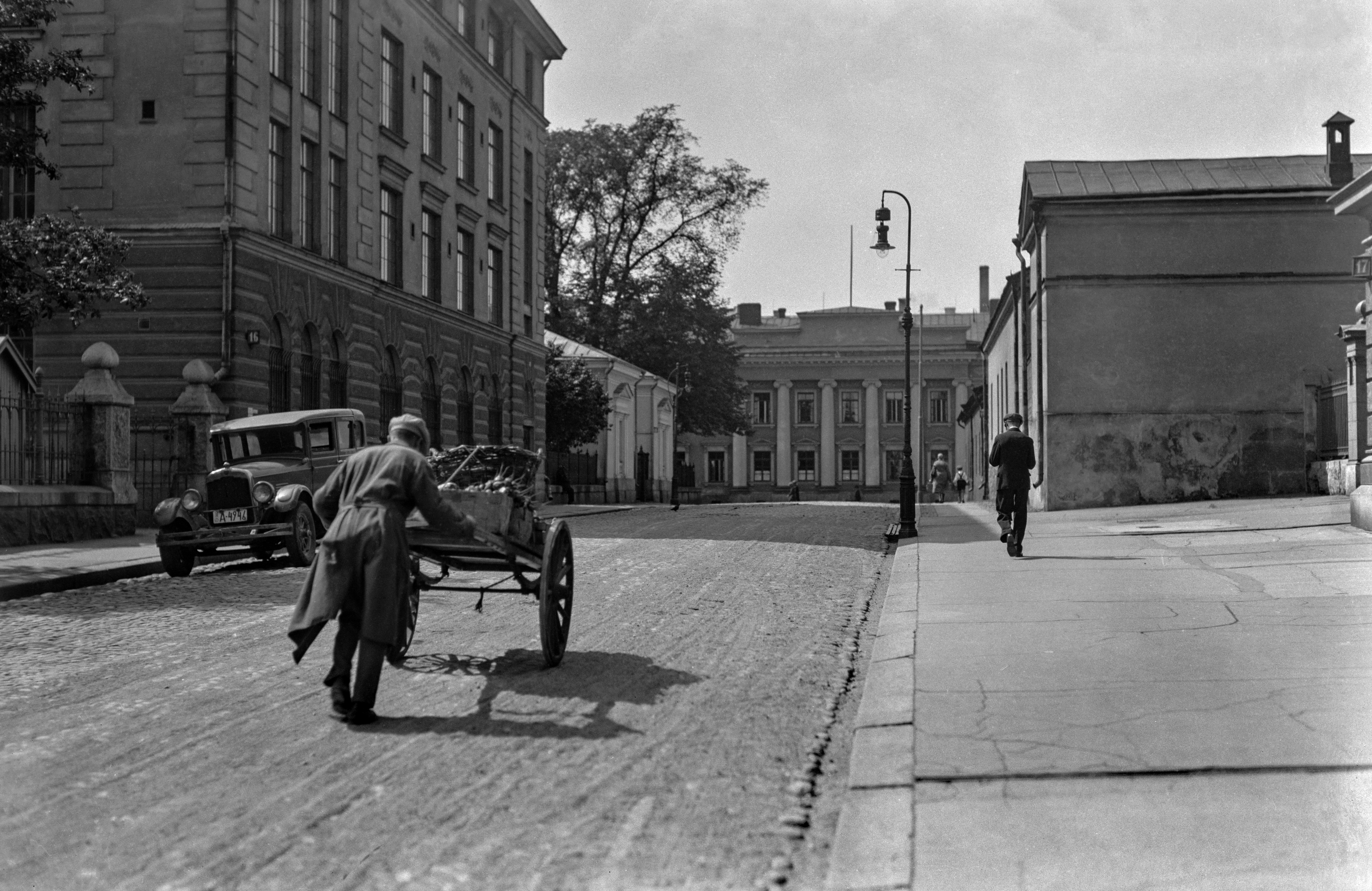 Rauhankatu 16, 18, 17, 19. Mies työntämässä kärryjä. Taustalla Unioninkatu 38 (Helsingin yliopiston neljäs sisätautien klinikka).