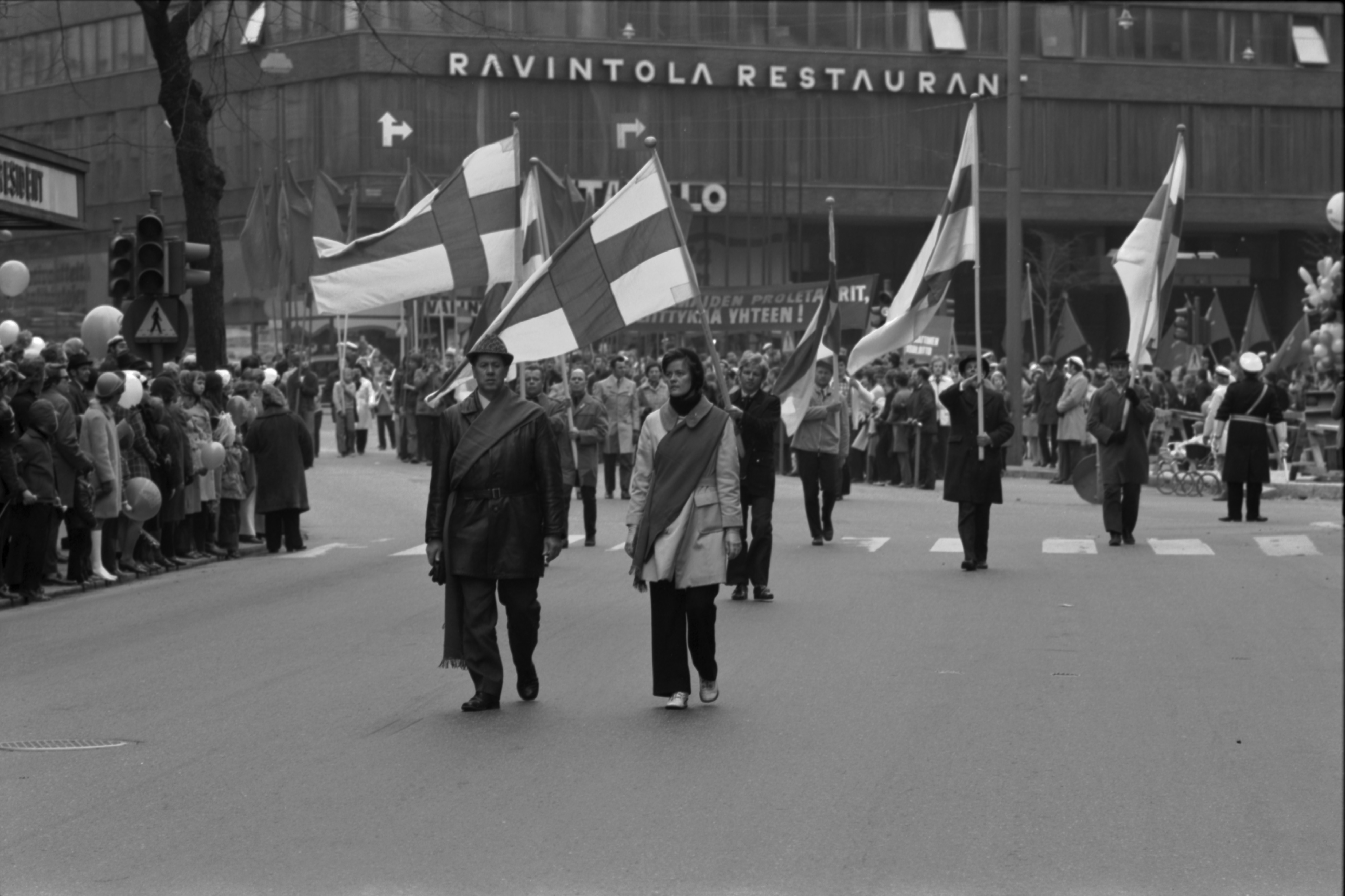 Pohjoisesplanadi. Työväen vappumarssikulkue kärjessään Suomen lippuja kääntymässä Mannerheimintieltä Pohjoisesplanadille 1.5.1972. Taustalla Mannerheimintie 10, hotelli Marskin talo.