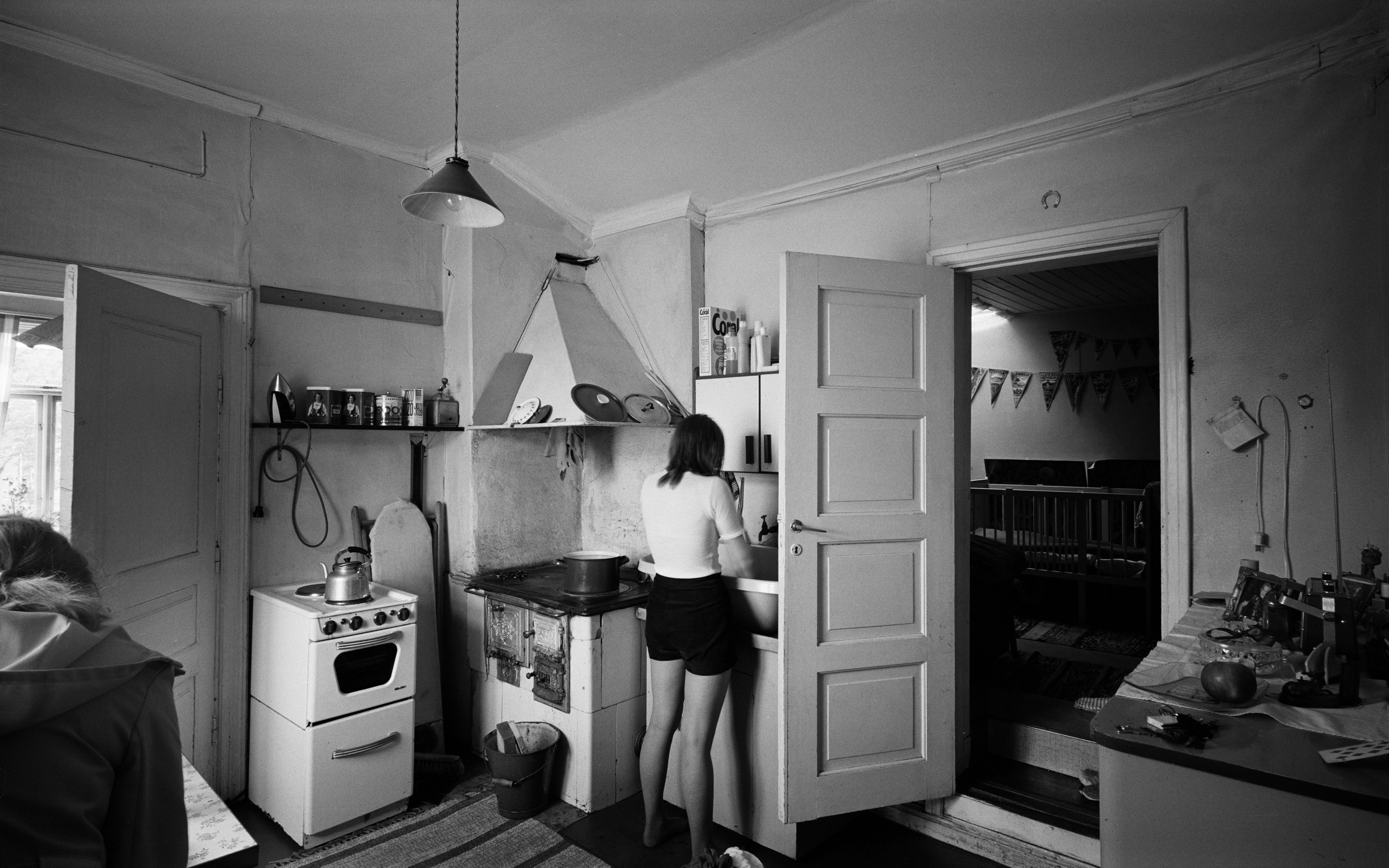 Ahtaaja Vilho Mickelssonin asunto, keittiö, taustalla makuuhuone. Kuvassa perheen kotiapulainen. Hertankatu 18. Pasila.