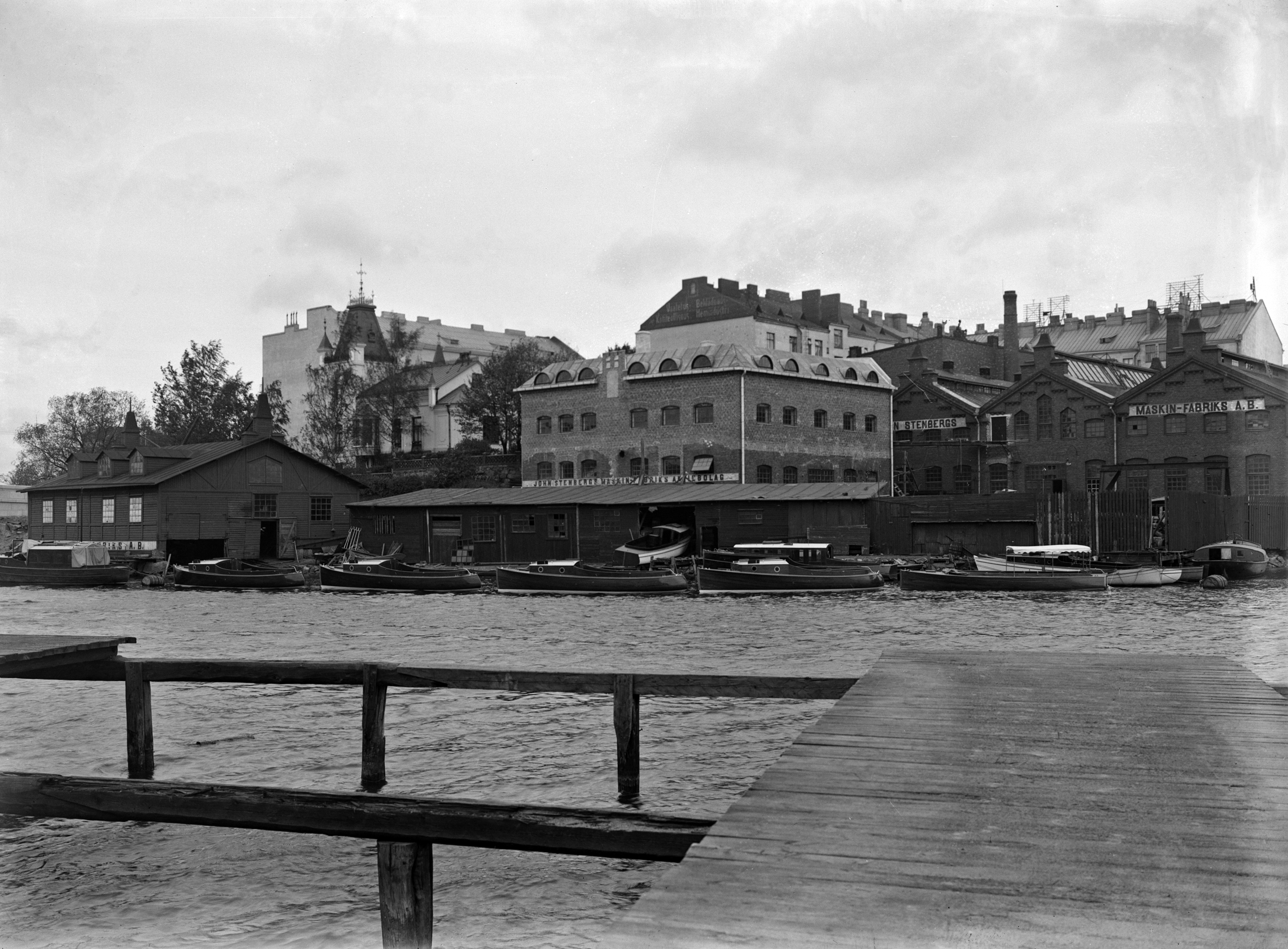 Näkymä John Stenbergin ranta 2:een (Pitkänsillanranta 1) Siltasaaressa. Etualalla venetelakka ja sen takana John Stenbergs Maskin-Fabrik Ab:n tuotantorakennuksia. Kuva on otettu vastapäiseltä rannalta Siltavuorenrannasta.