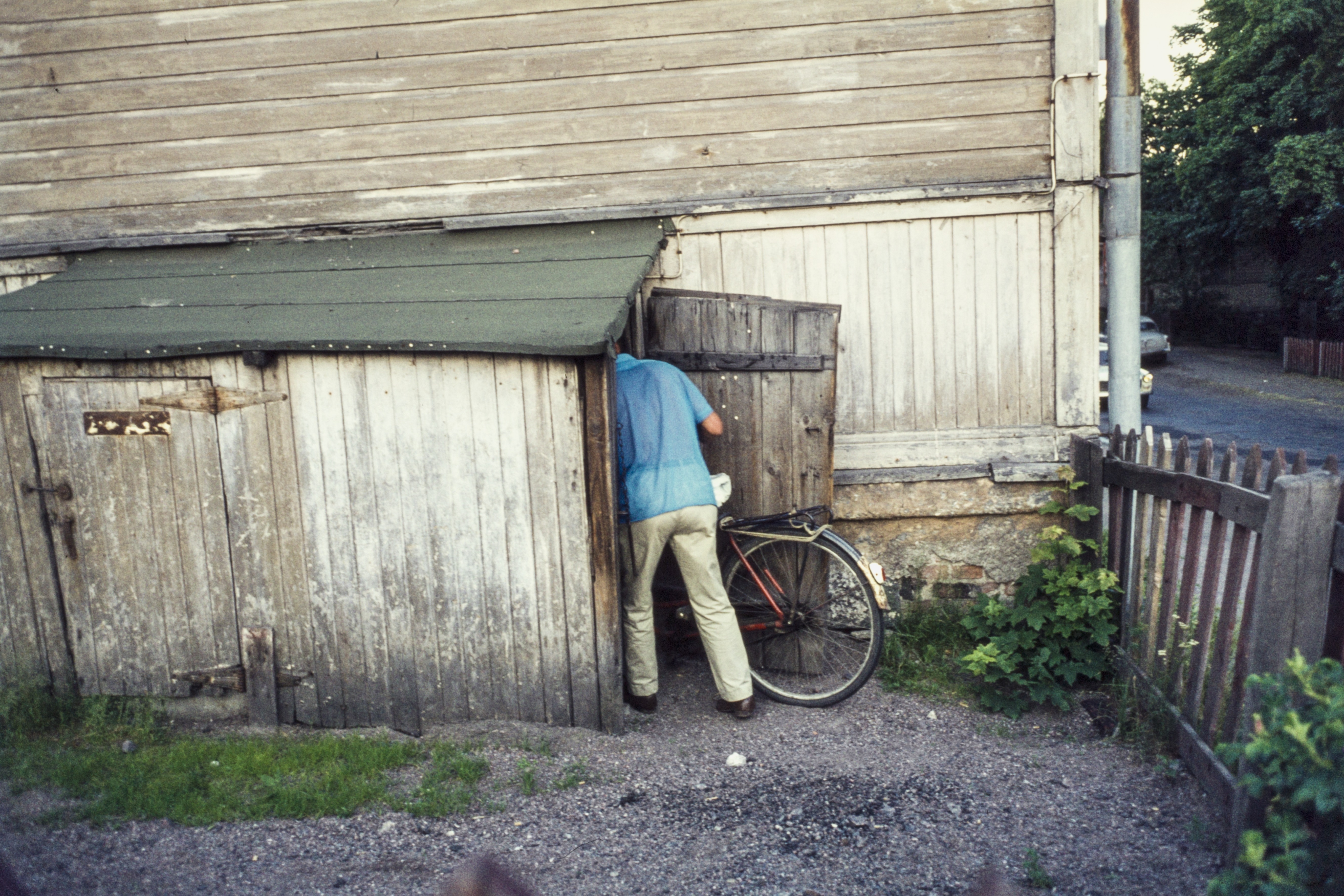 Mies taluttamassa polkupyöräänsä varastoon Puu-Pasilassa, Hertankatu 13. Valokuva on otettu rakennuksen Susannankadun puoleisesta päädystä.