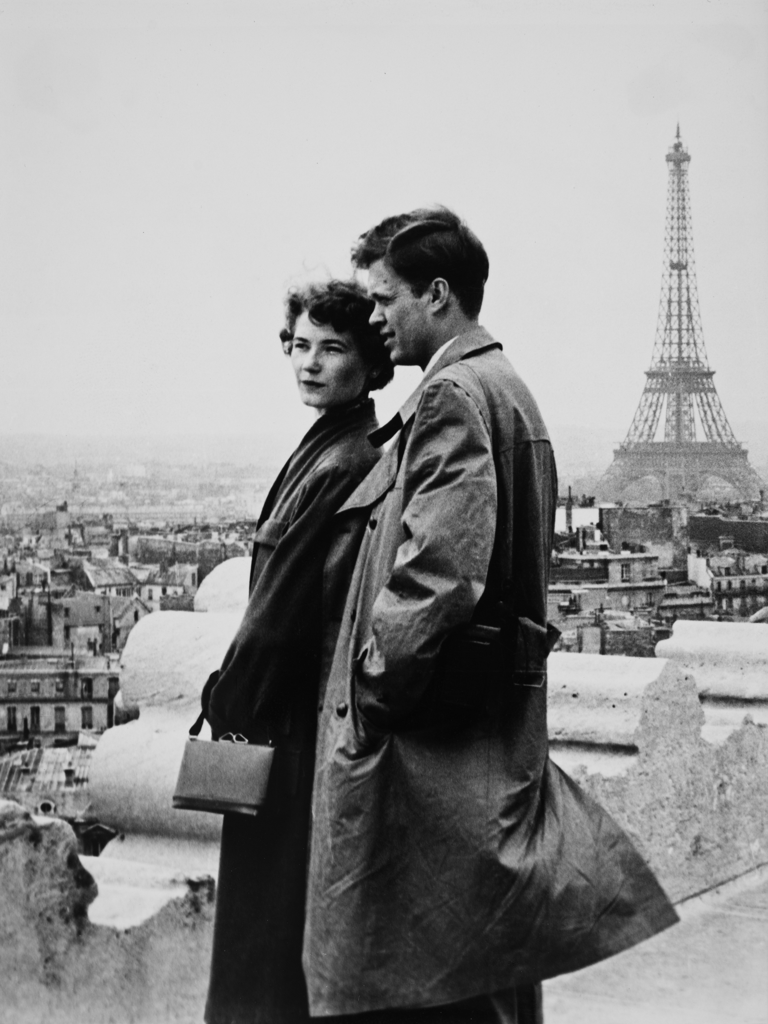 Pariskunta poseeraa Riemukaaren katolla häämatkalla Pariisissa, Eiffel-torni taustalla.