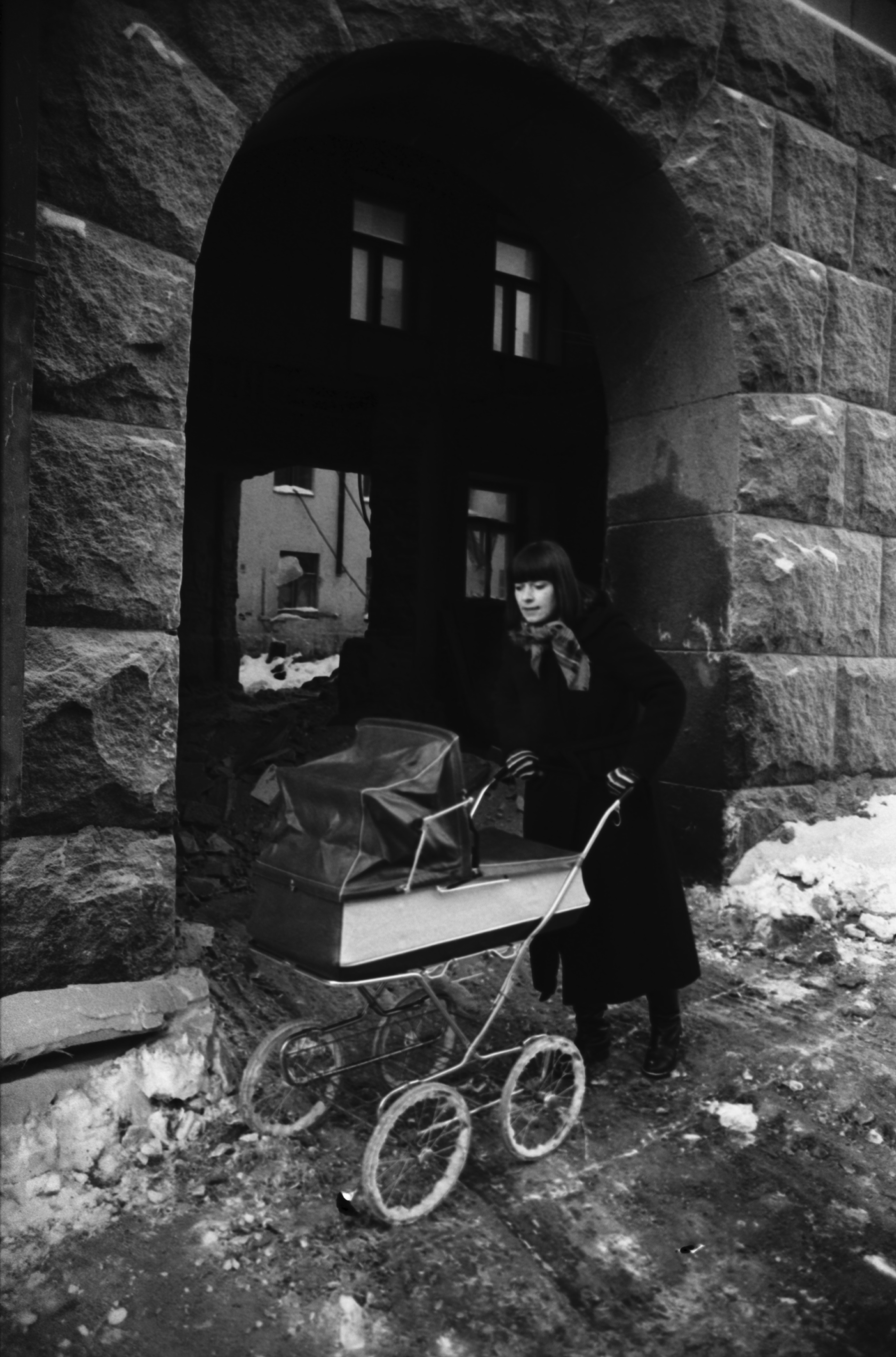 Meritullinkatu 10b. Äiti (Etta Harvilahti) työntämässä lastenvaunuja remontissa olevan Opetusministeriön talon porttikäytävän edustalla Meritullinkadulla.