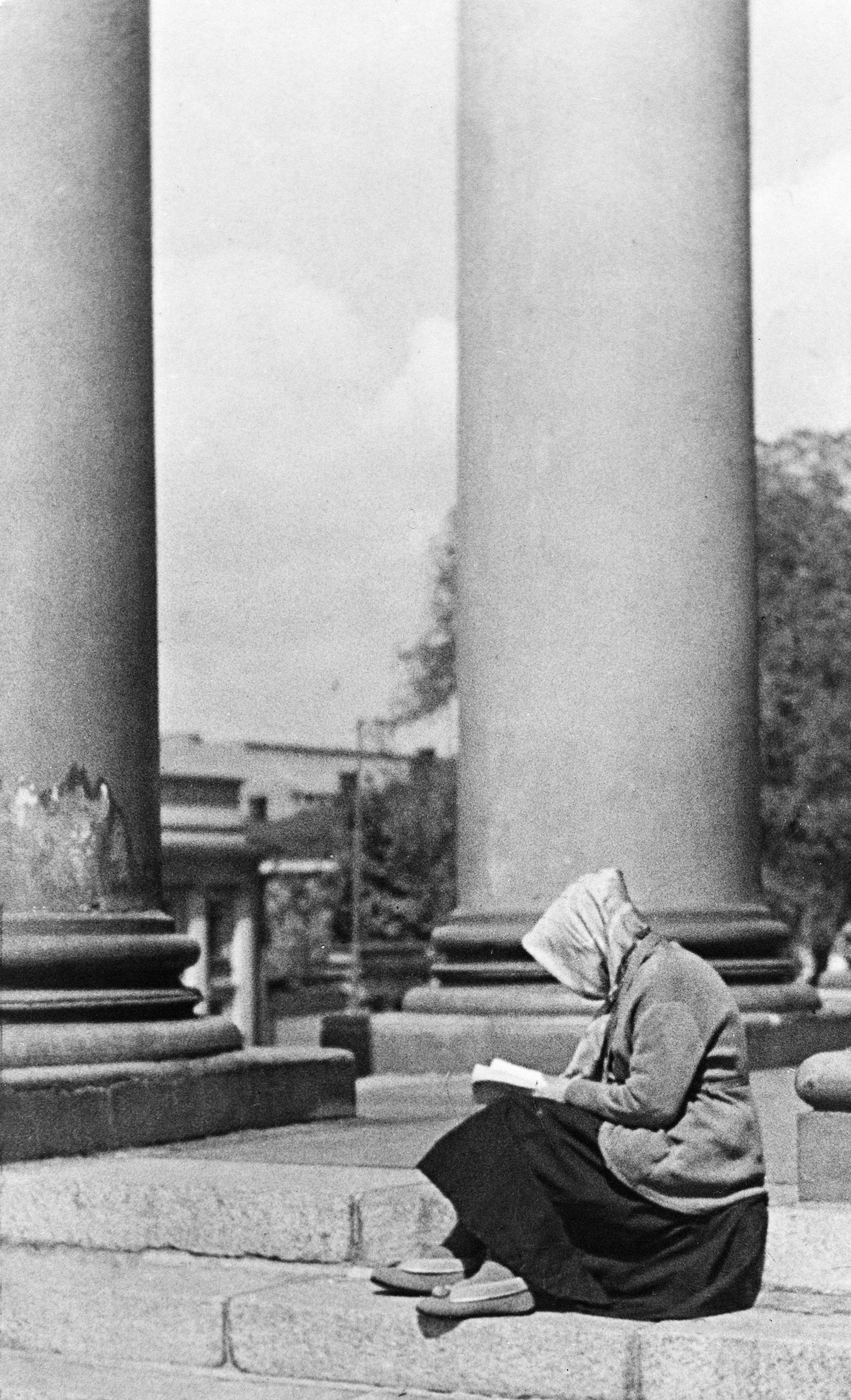 Nainen lukemassa Helsingin Tuomiokirkon (=Nikolainkirkko, Suurkirkko) portailla.