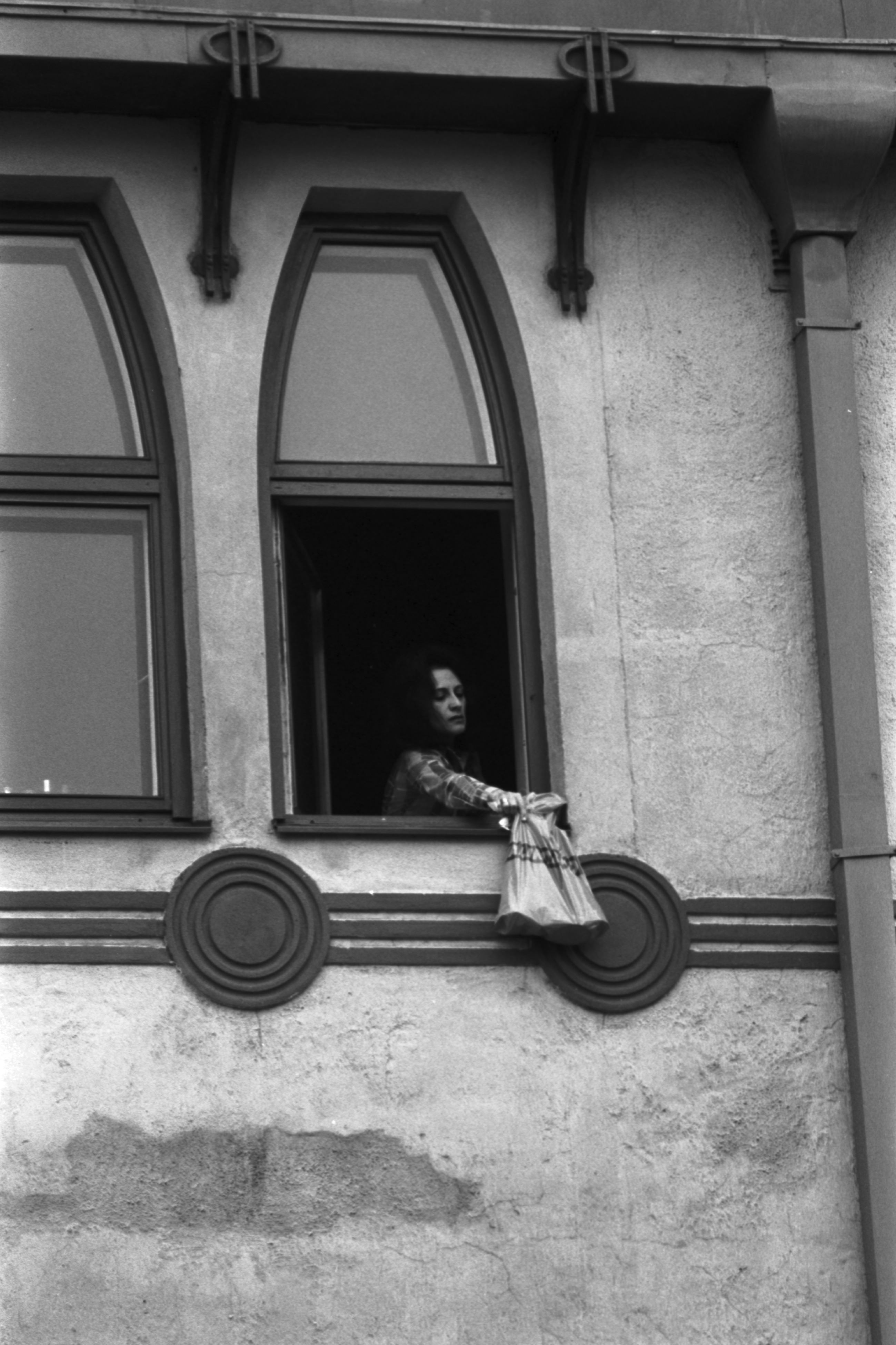 Meritullinkatu 26. Nainen ripustamassa Valintatalon muovikassia asuntonsa ikkunan ulkopuolelle Meritullinkatu 26:n ylimmässä kerroksessa.