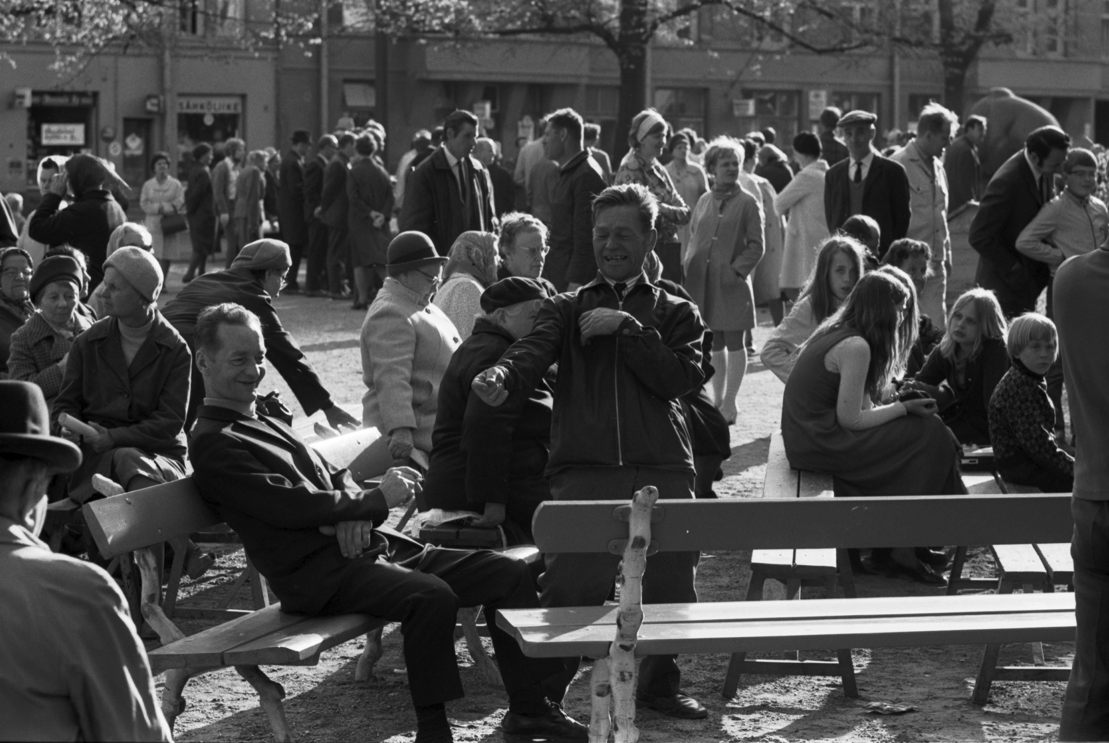 Karhupuisto. Yhden miehen show penkeillä istuvien ihmisten keskellä aurinkoisessa Karhupuistossa puistotapahtuman aikaan.