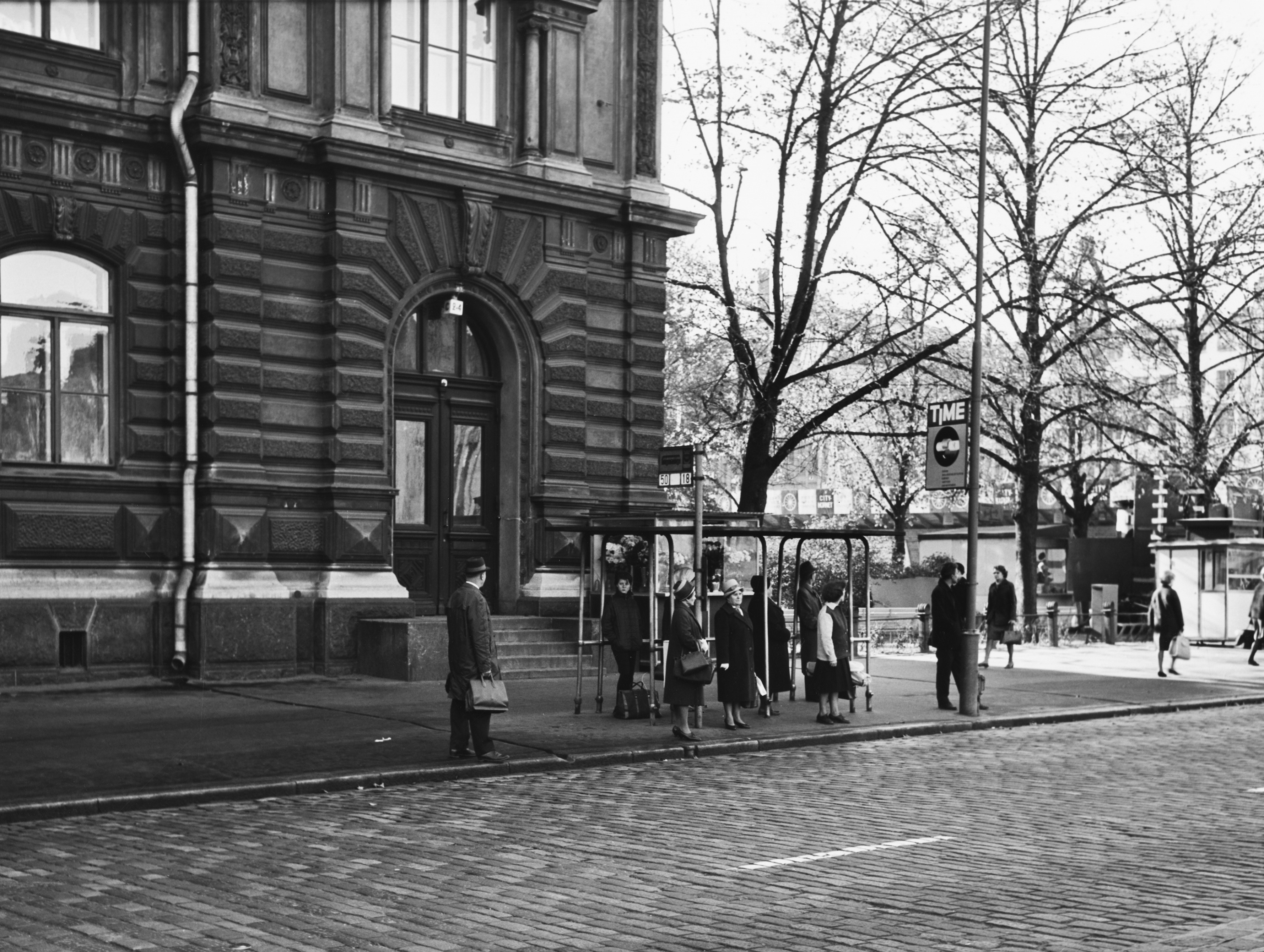 Ihmisiä linjojen 18 ja 50 pysäkillä Kaivokadulla Ateneumin edustalla.