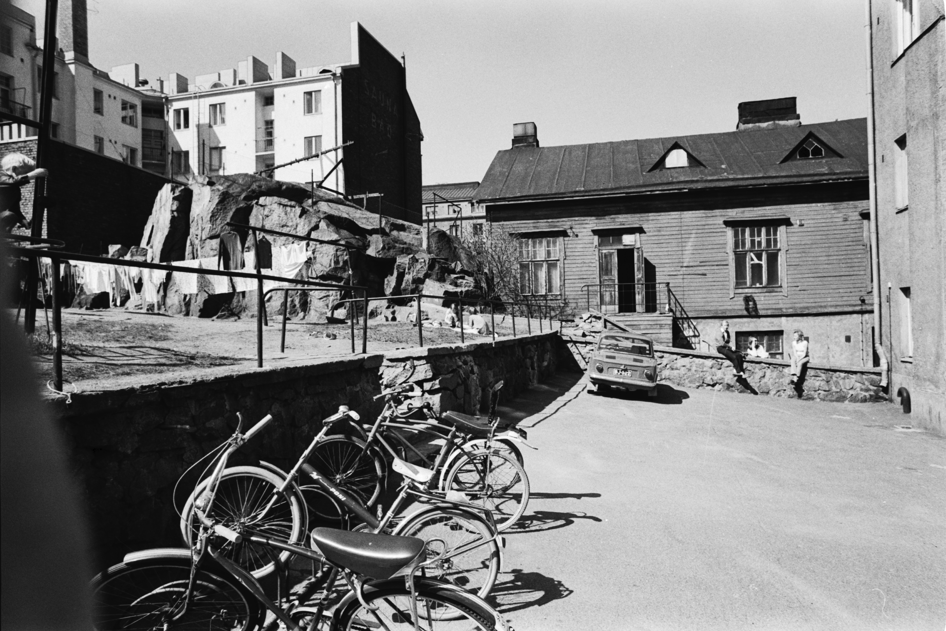 Fleminginkatu 14. Näkymä Fleminginkatu 14:n pihalta. Etualalla polkupyöriä, taaempana Fleminginkatu 16:n puutalo ja kallio. Taustalla kerrostaloja.