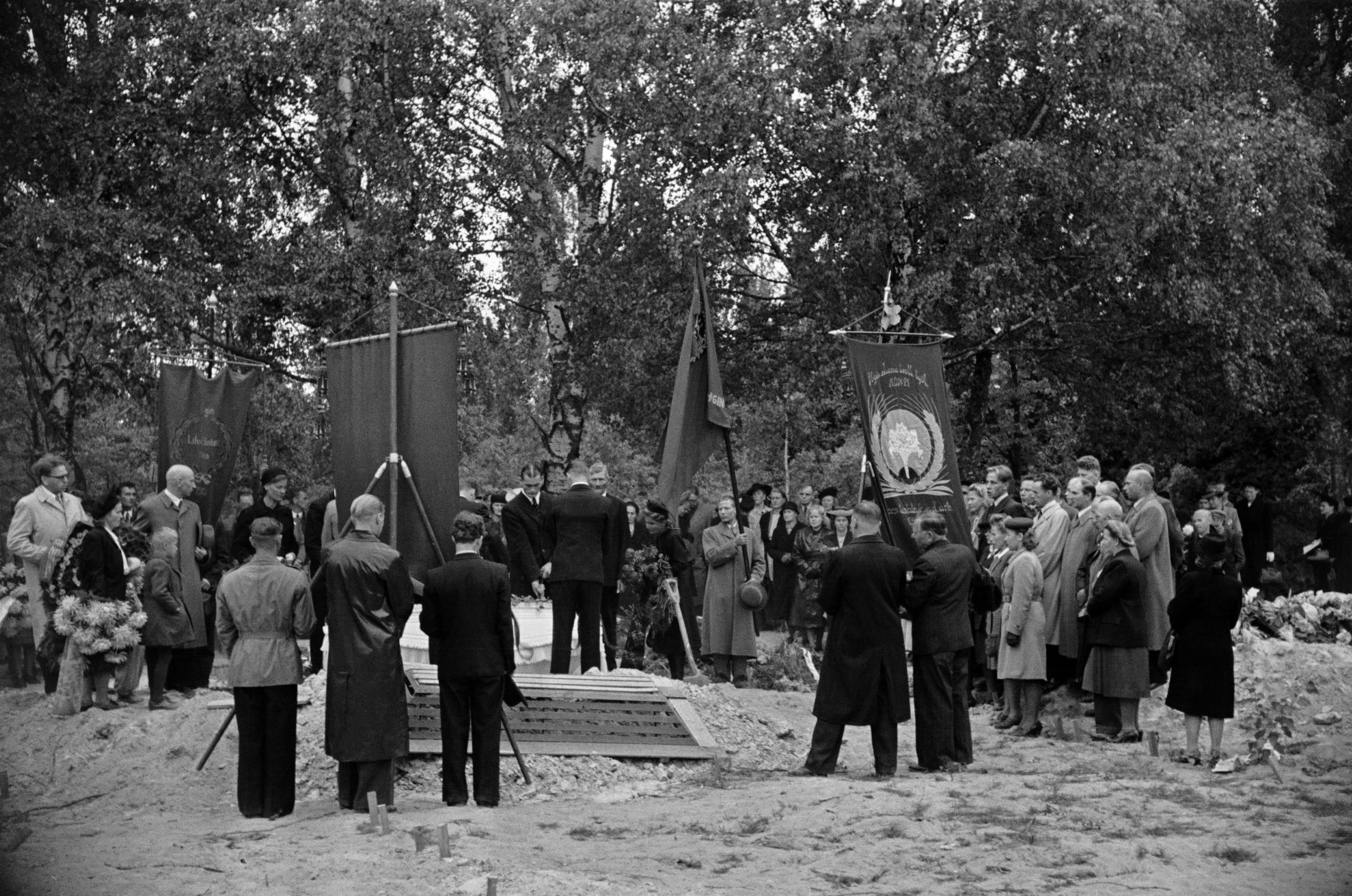 Pohjoinen hautausmaa (=Malmin hautausmaa), Arvi Heinon hautajaiset. Arkkua lasketaan hautaan, miehet kantavat ammattiyhdistysten lippuja. Oikealla Helsingin juomateollisuustyöläisten ammattiosasto 21:n lippu.