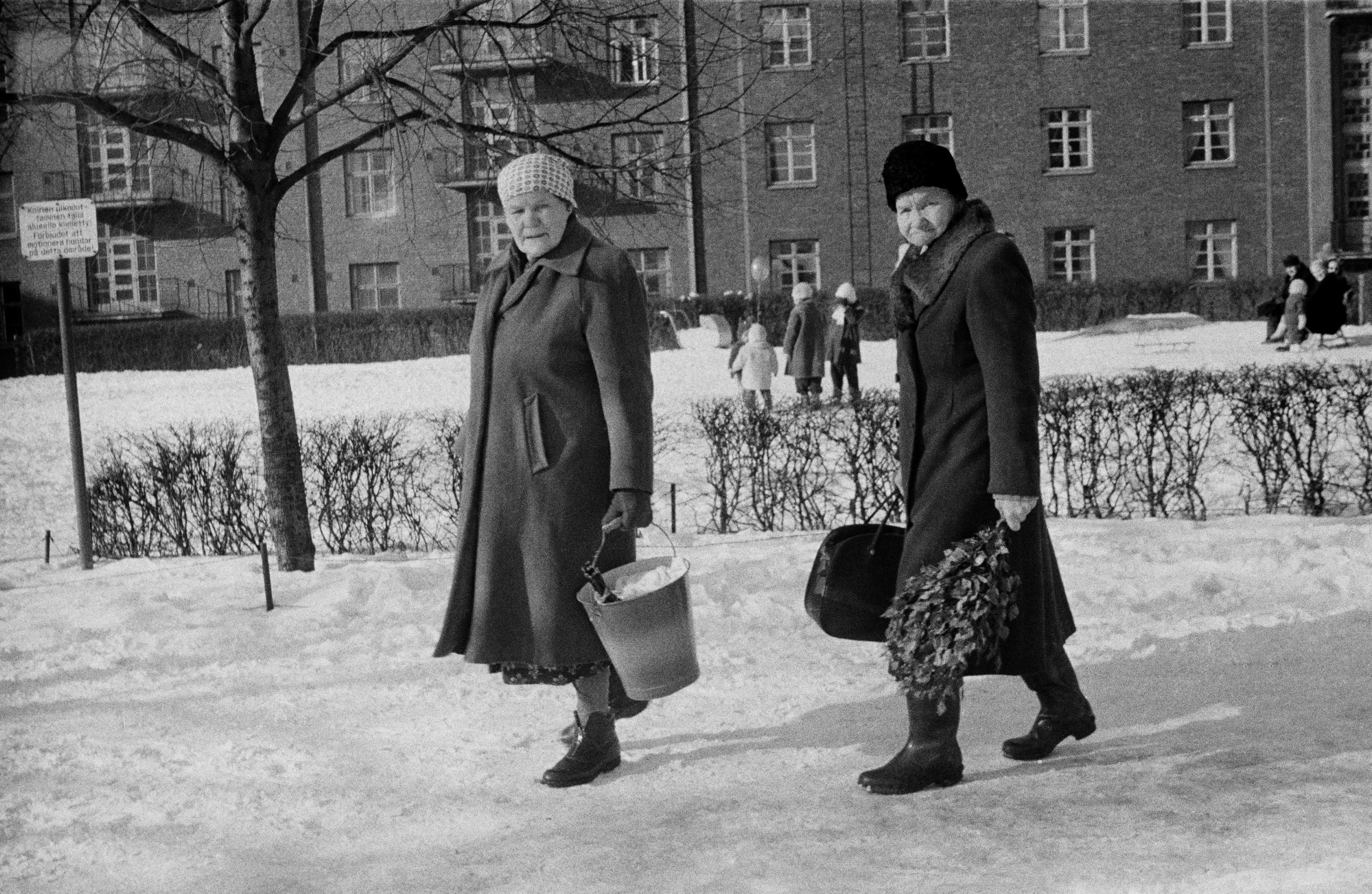 Kaksi naista Franzéninkadulla matkalla saunaan. Taustalla lapsia ja aikuisia Franzénin puistikossa sekä kerrostalo Adolfinkatu 13 (=Helsinginkatu 14).