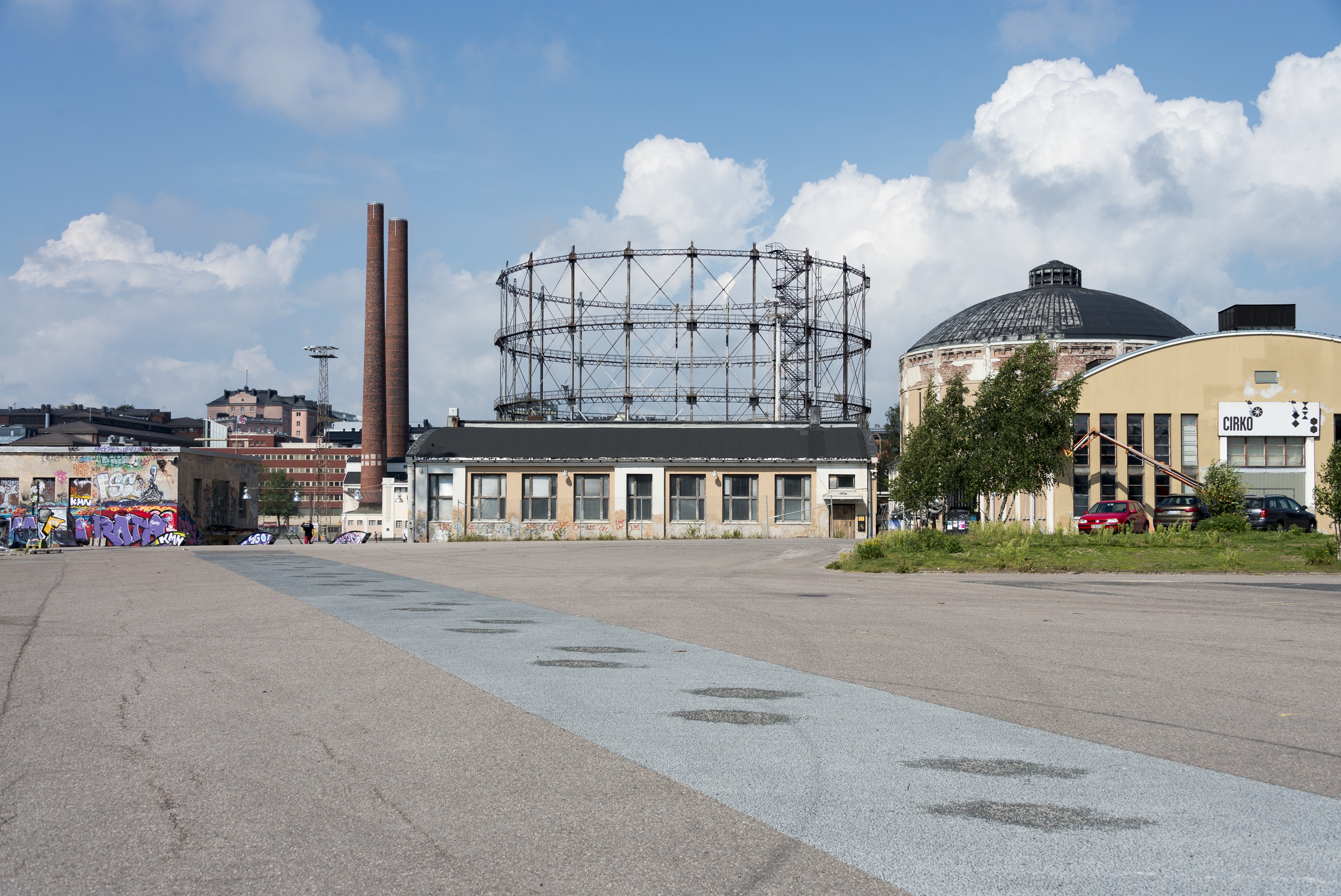 Kalasataman dokumentointi. Suvilahden voimalaitoksen alue nähtynä idästä uuden Kalasataman asuinalueen suunnasta, kaasukellot ja voimalaitoksen rakennuksia, vasemmalla graffitiseinä.