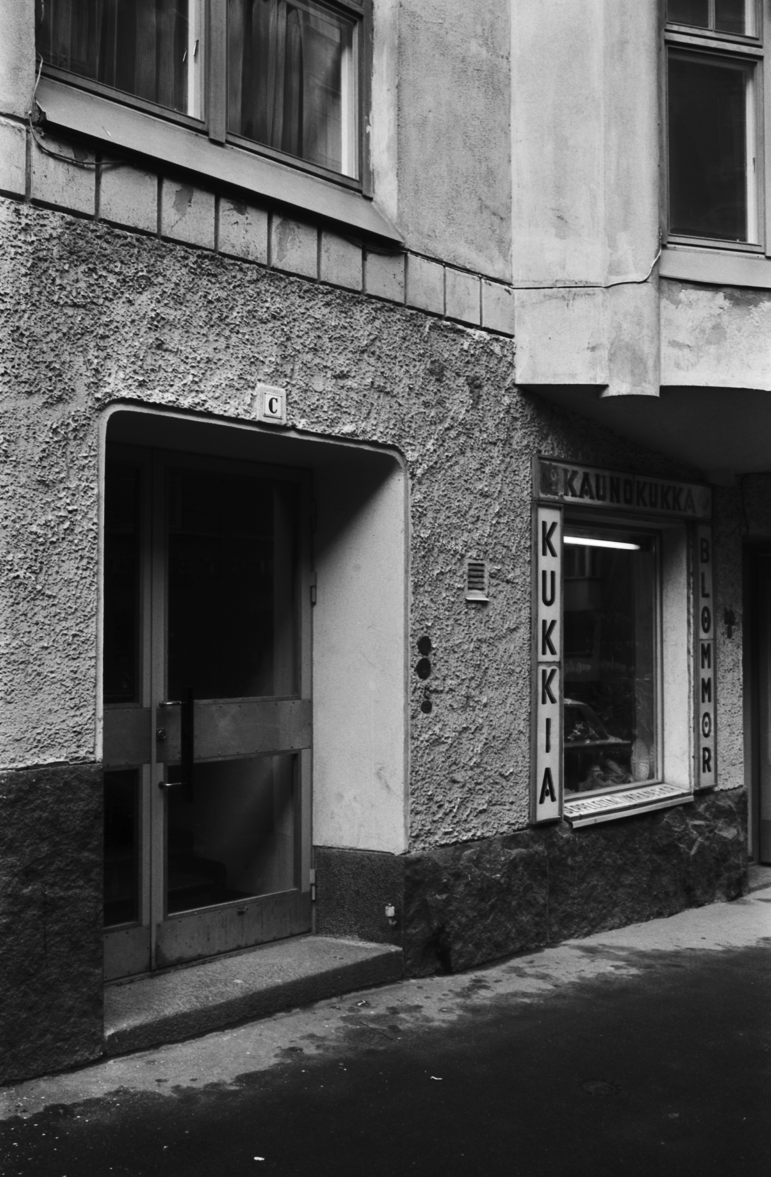Liisankatu 9. Liisankatu 9:n jugendtalon kadun tason julkisivua - C-portaan ulko-ovi ja kukkakauppa Kaunokukan näyteikkuna.