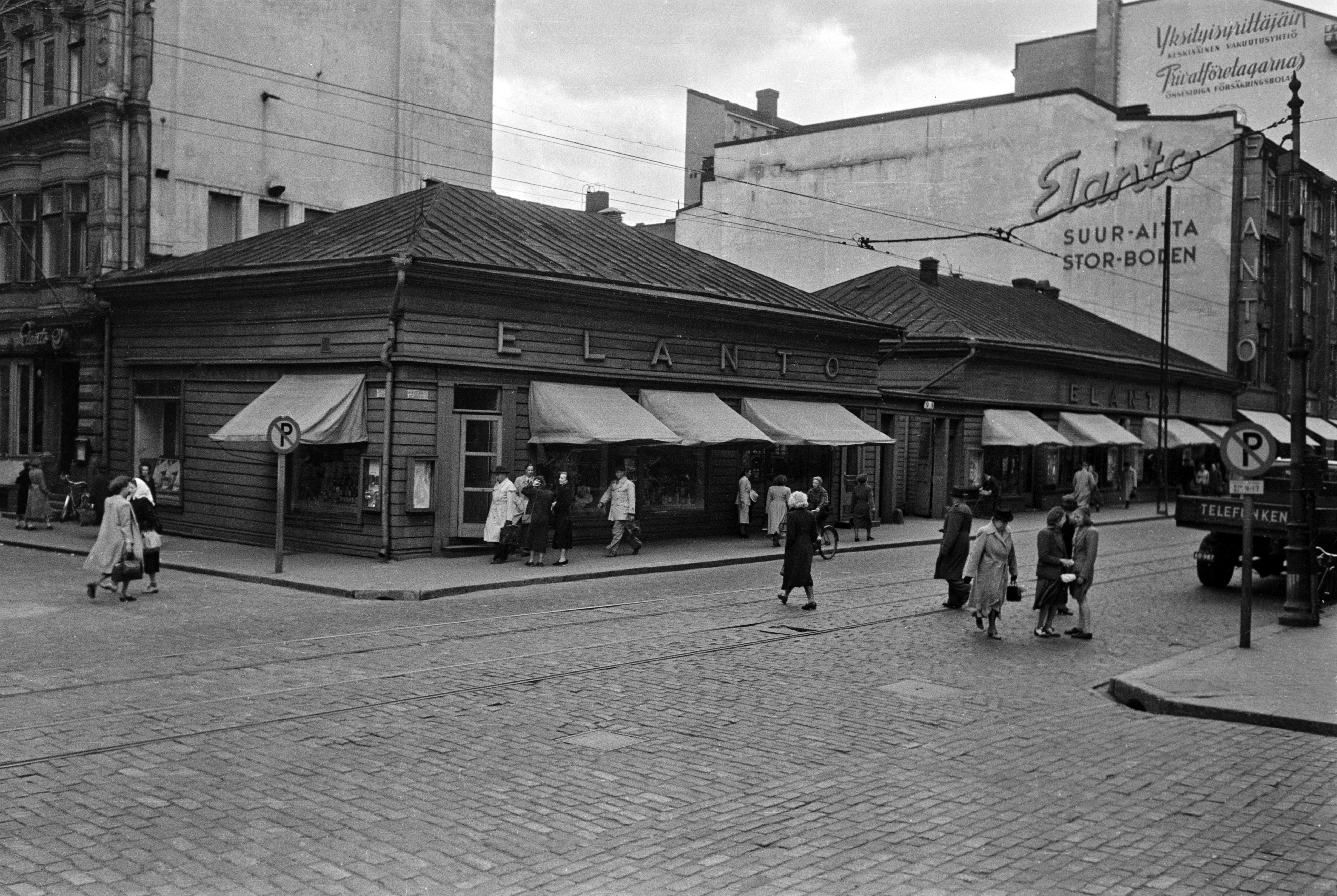 Aleksanterinkatu 9. - Kluuvikatu 5. Elannon myymälä ja Elannon suur-aitta. Puurakennukset purettiin syksyllä 1950 ja paikalle rakennettiin Elannon tavaratalo.