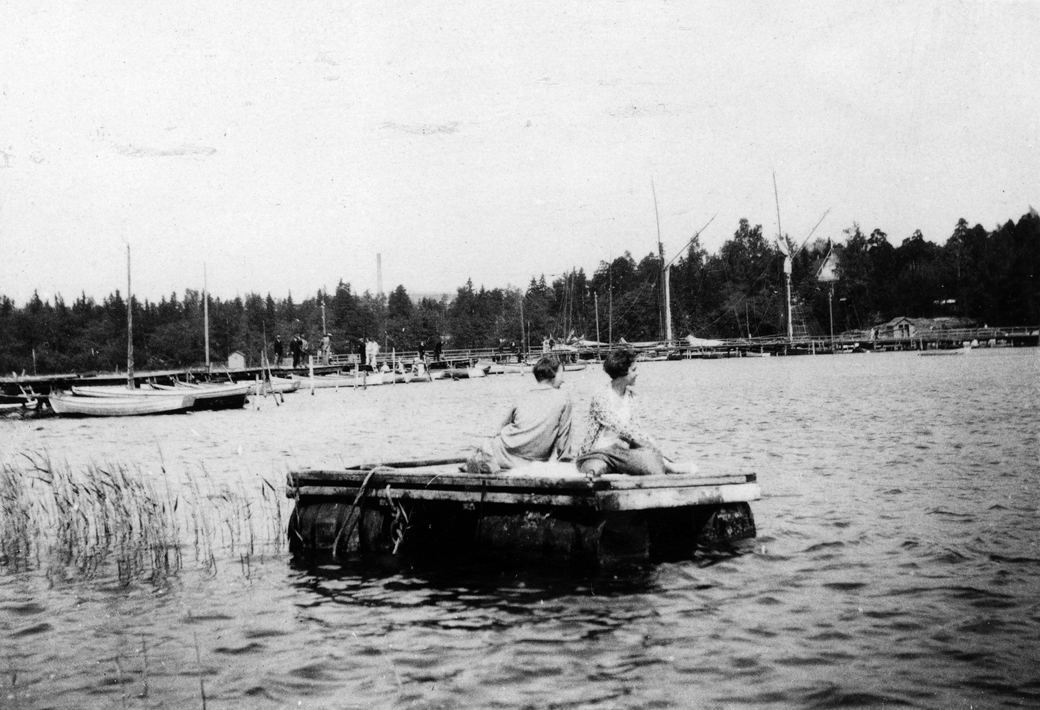 Humallahti. Kaksi nuorta naista lautalla istumassa. Taustalla venesatama.