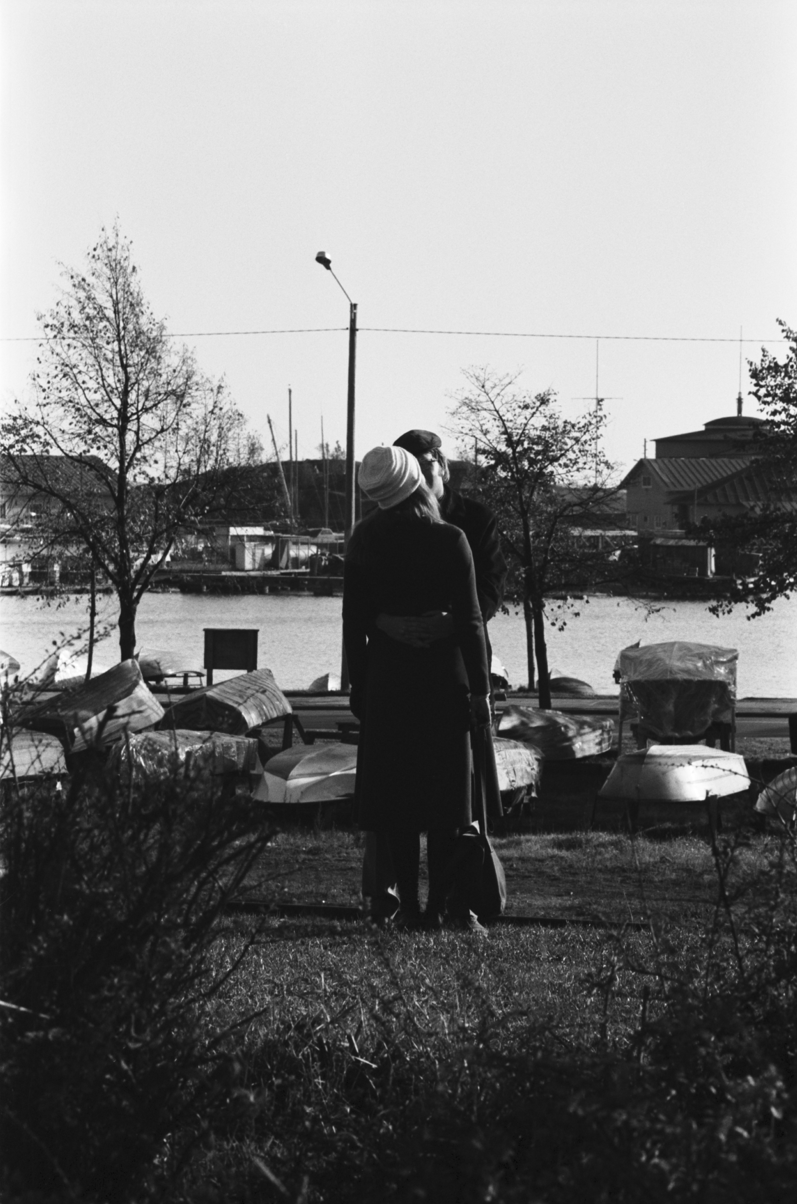 Ullanlinna, Fredrik Stjernvallin puisto. Nainen ja mies seisomassa halailemassa Fredrik Stjernvallin puistossa. Näkymä Merikadun suunnalta etelään Merisatamaan päin. Taustalla mm. Liuskasaari.